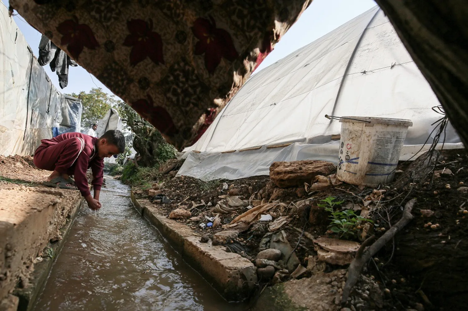 28 October 2022, Lebanon, Bebnine: A Syrian refugee boy washes his hands in a contaminated water conduit near their tent at a refugee camp in the northern Lebanese village of Bebnine. (dpa)