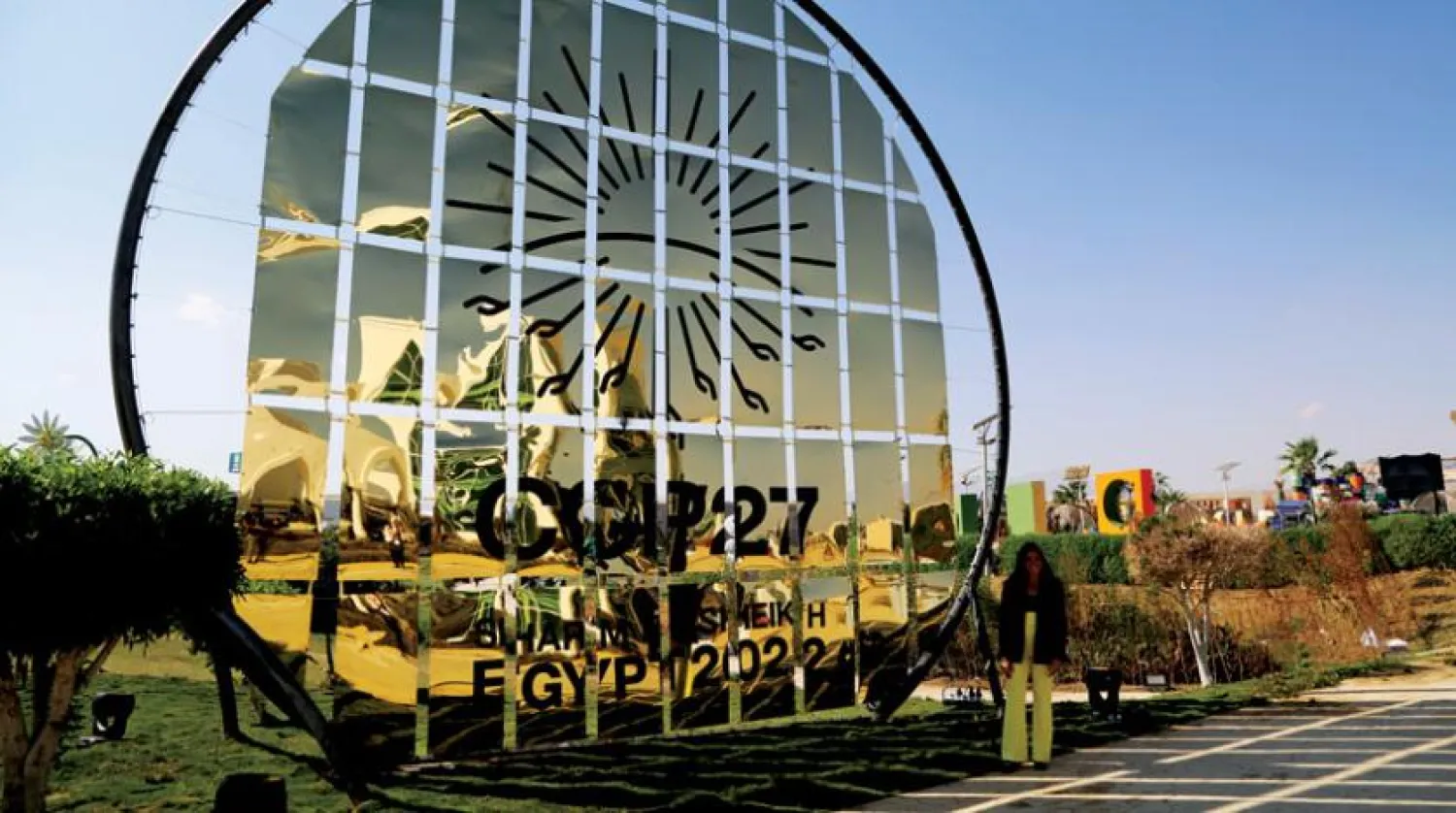 Şarm eş-Şeyh'te COP27 logosu önünde duran bir kadın (AP)