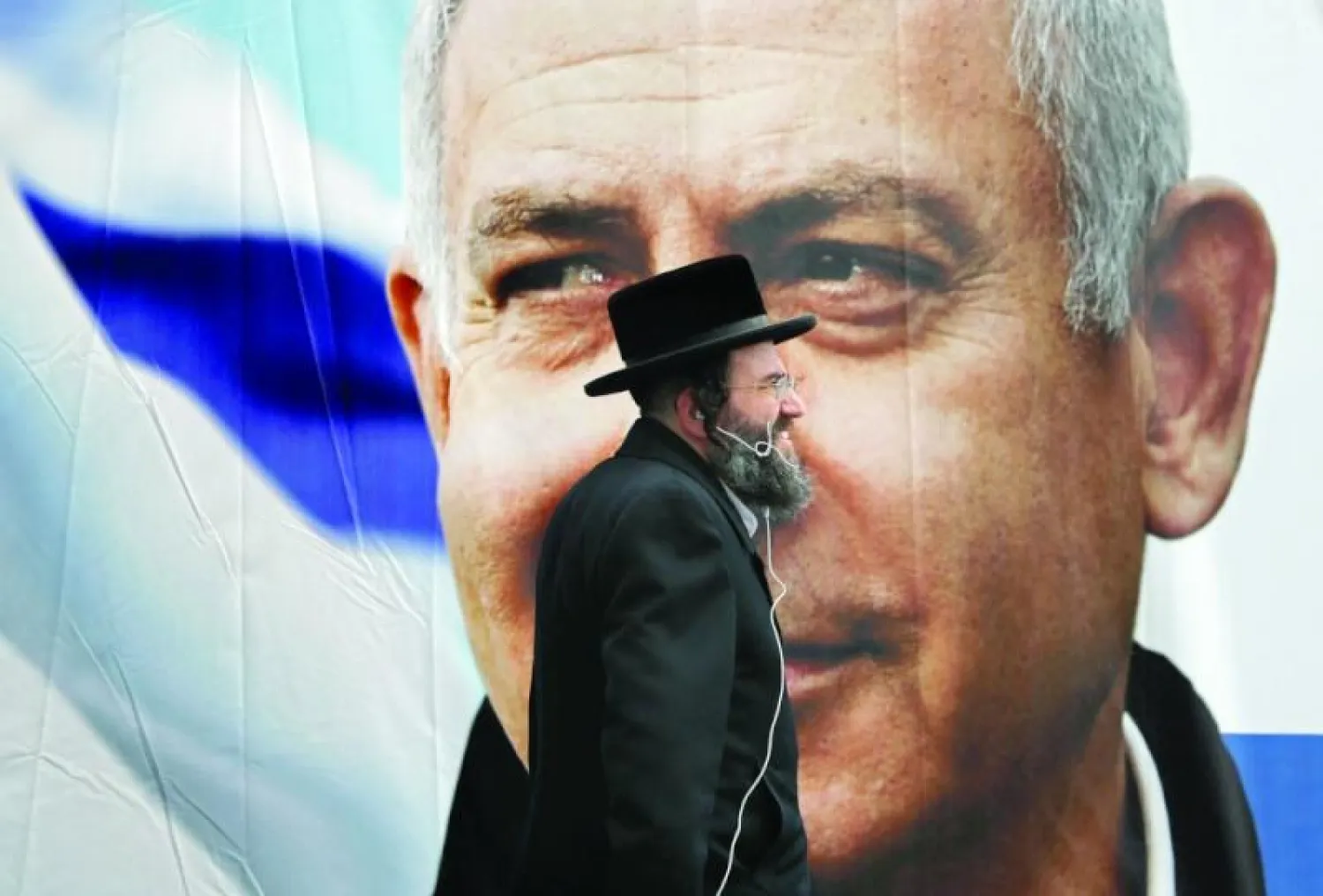 متدين يهودي يمر أمام ملصق لنتنياهو (أ.ف.ب)