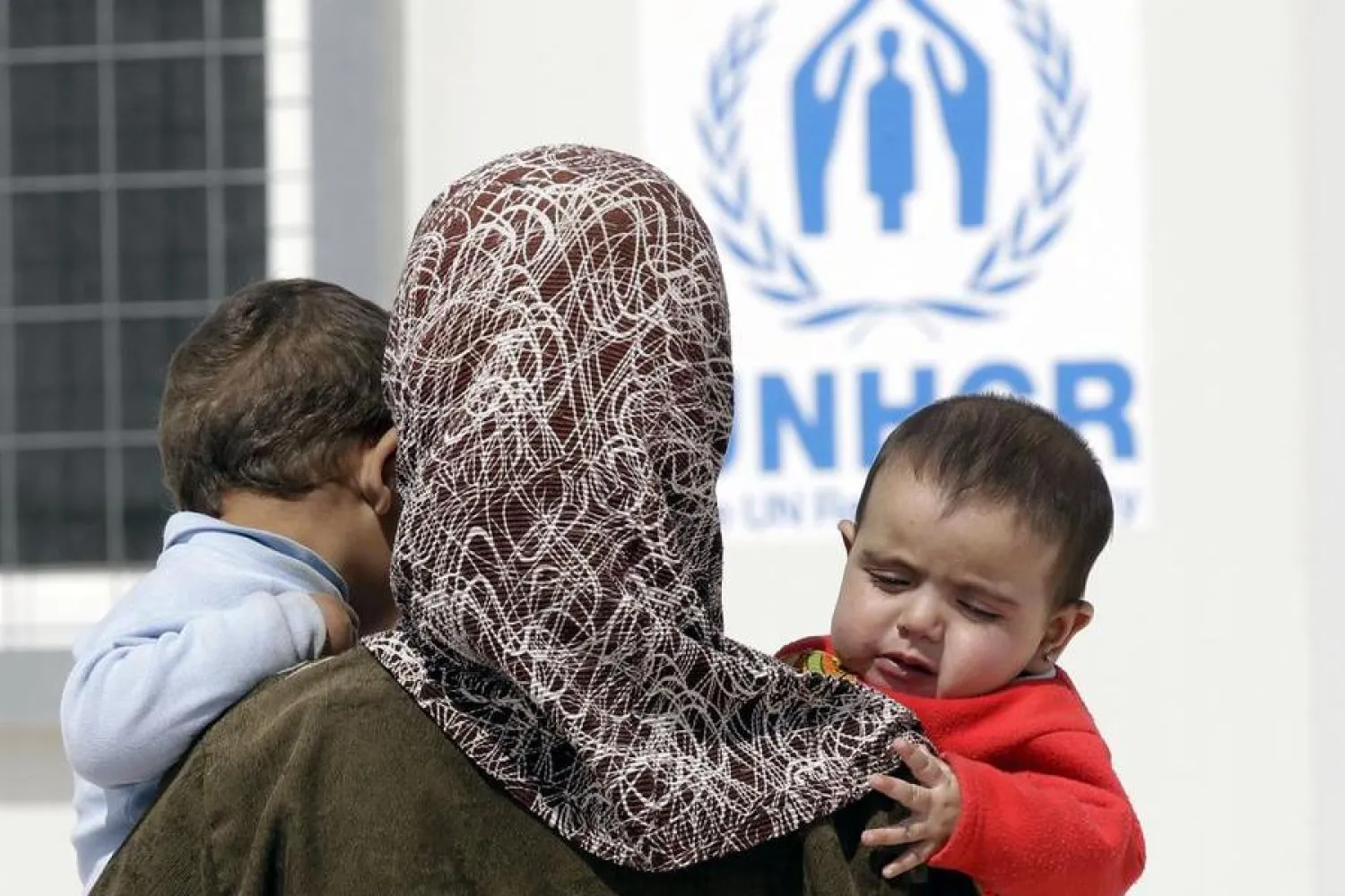 A Syrian refugee holds her kids as she arrives to register at an office of the UNHCR at the newly-opened Mrigeb al-Fuhud refugee camp ,20 km east of the city of Zarqa on April 10, 2013. (Photo by KHALIL MAZRAAWI / AFP)
