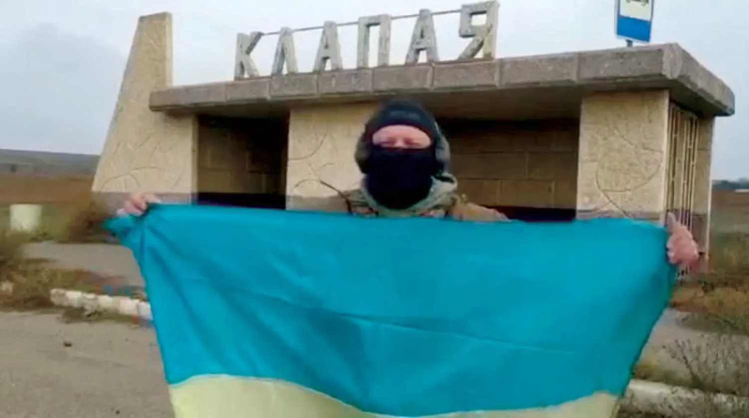 جندي أوكراني في خيرسون يحمل علم أوكرانيا احتفالاً بعودة المدينة إلى سيطرة كييف (رويترز)