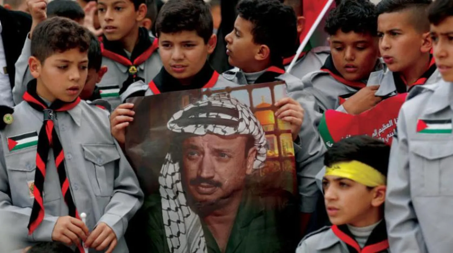 Palestinian scouts hold a picture of the late Palestinian leader Yasser Arafat on the 18th anniversary of his death next to his tomb in the the West Bank city of Ramallah, 10 November 2022, during a rally of Fatah movement supporters to commemorate his memory. EPA/ATEF SAFADI