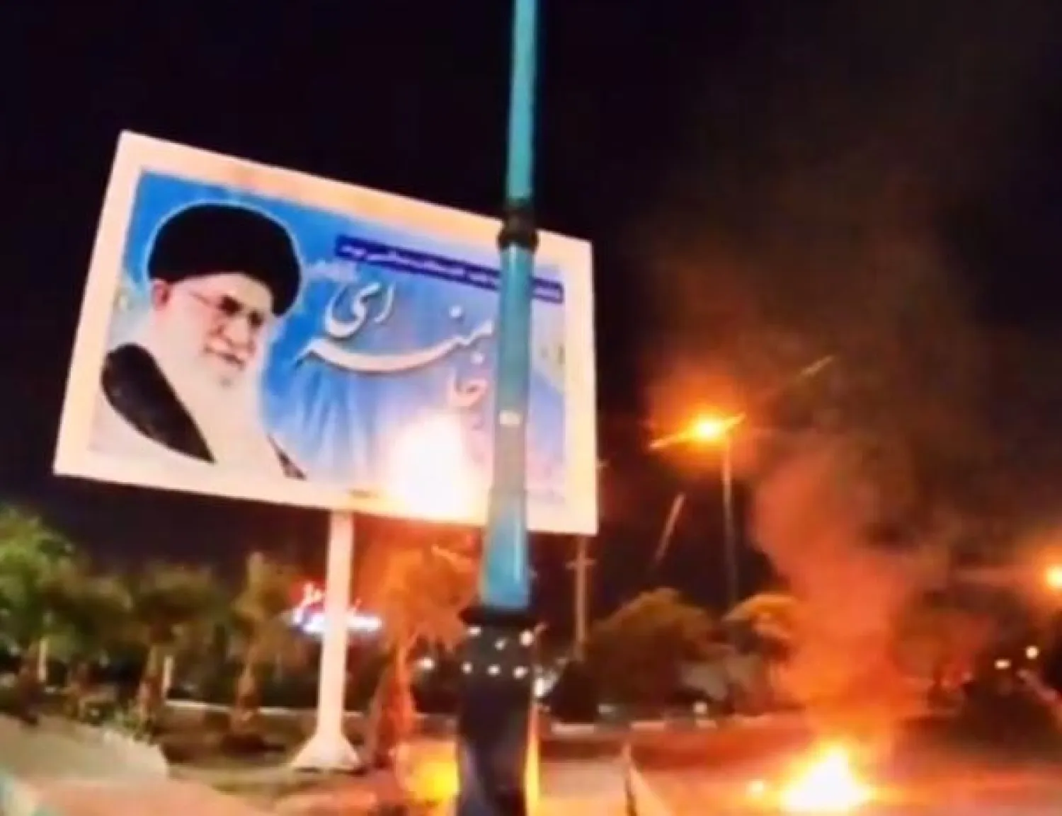 نيران تلتهم لوحة إعلانية تحمل صورة المرشد الإيراني علي خامنئي (تويتر)