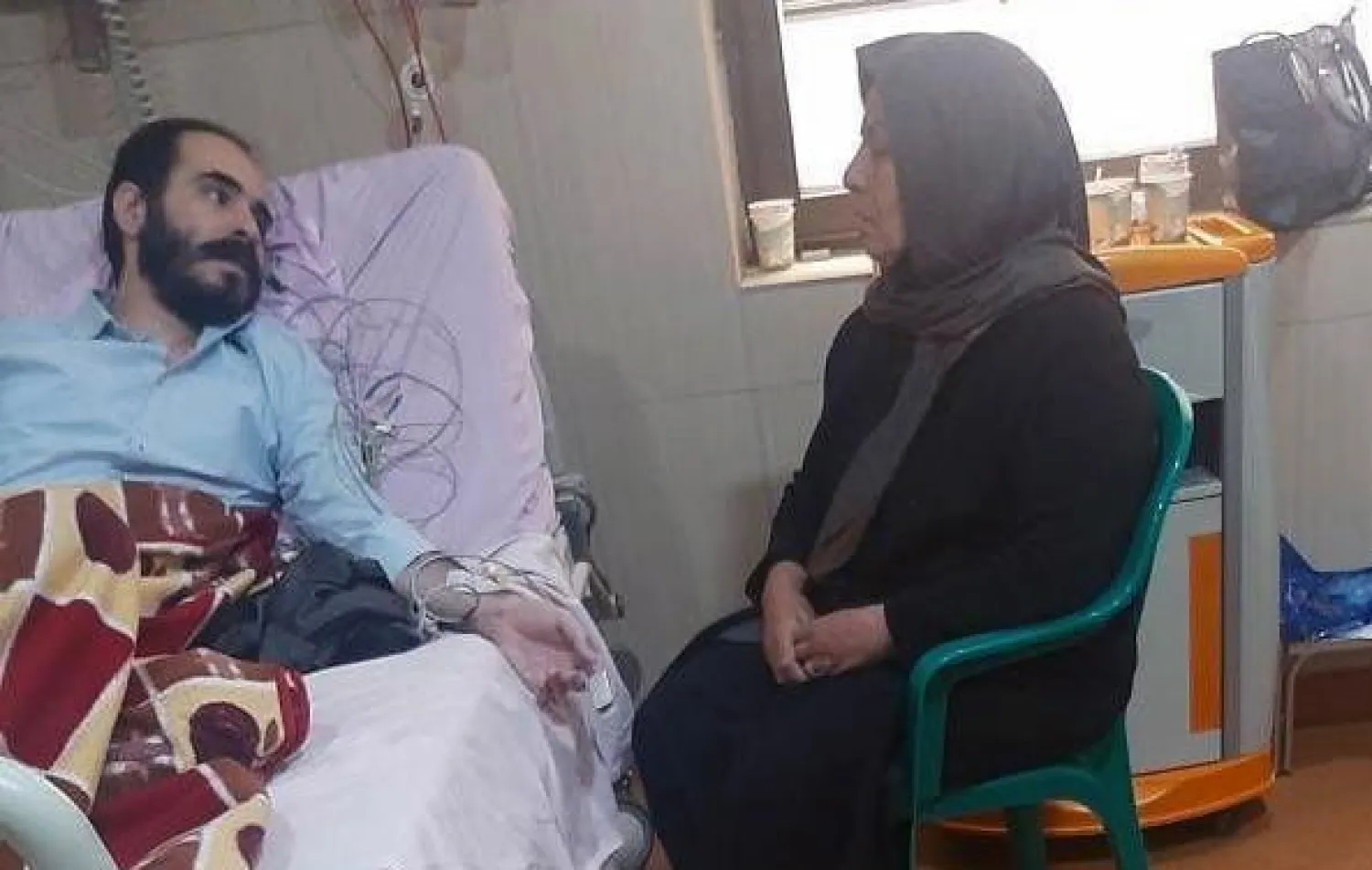 رونقي وإلى جانبه والدته في احد مستشفيات طهران أمس (إ.ب.أ)