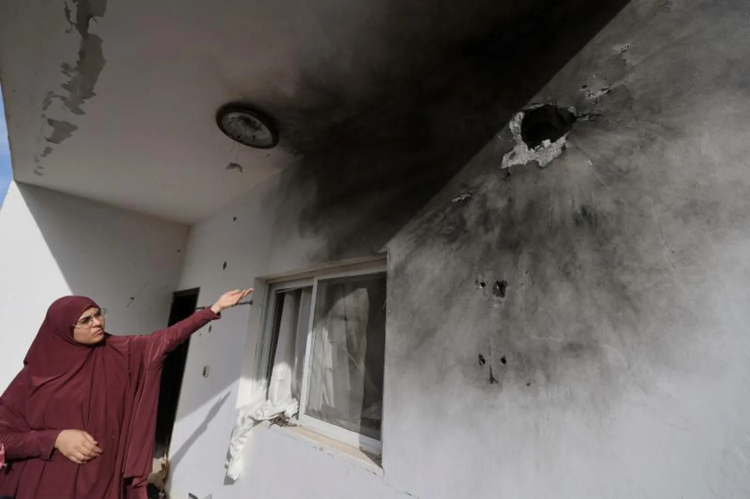 سيدة فلسطينية تشير إلى آثار خلفتها العملية العسكرية الإسرائيلية على منزل في مدينة جنين (أ.ف.ب)
