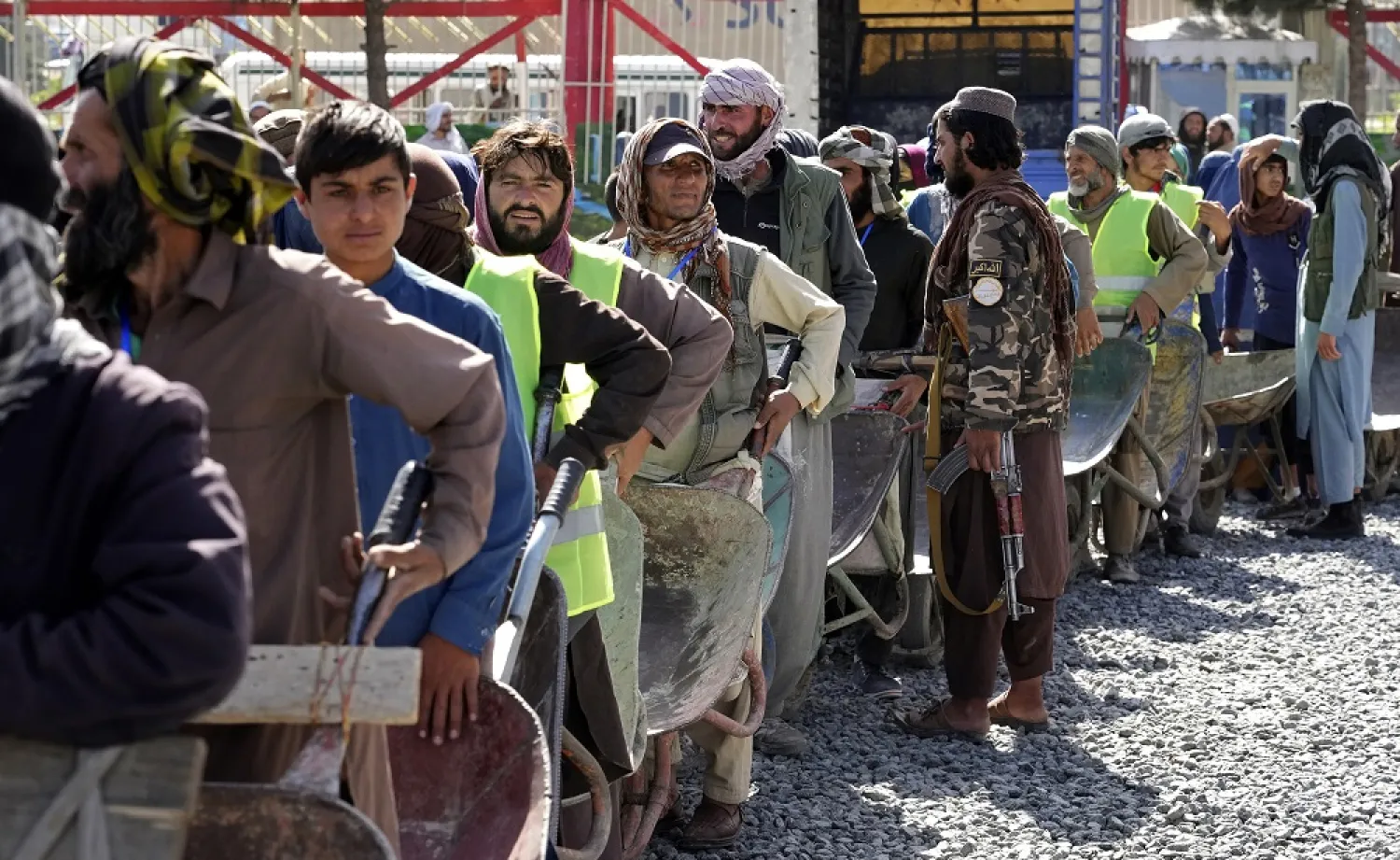 A Taliban fighter stands guard as people wait in line to receive food rations distributed by a Saudi humanitarian aid group, in Kabul, Afghanistan, Monday, April 25, 2022. (AP)