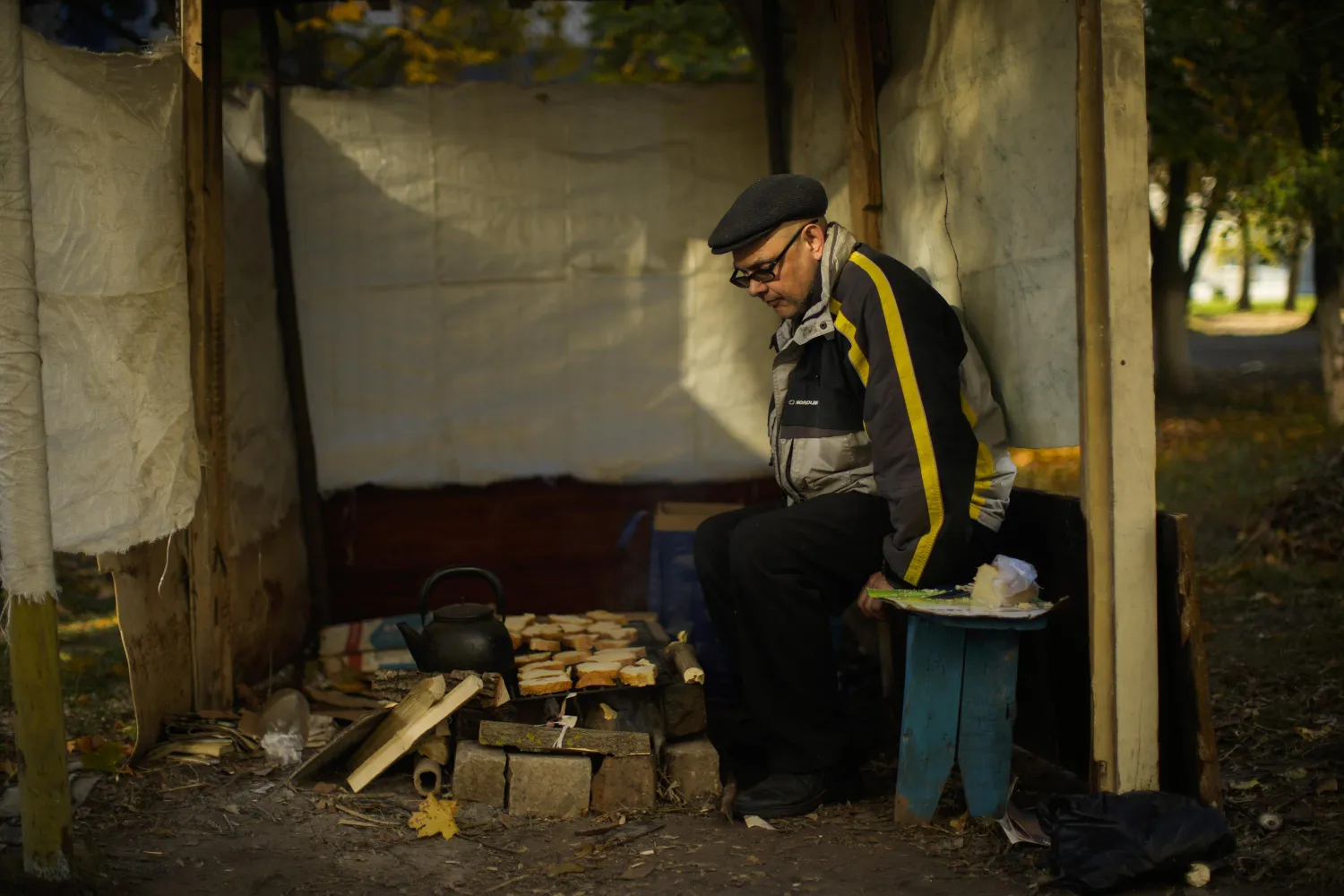 Anton Sevrukov, 47, toasts bread over fire in a makeshift stove in Kivsharivka, Ukraine, Sunday, Oct. 16, 2022.(AP Photo/Francisco Seco)
