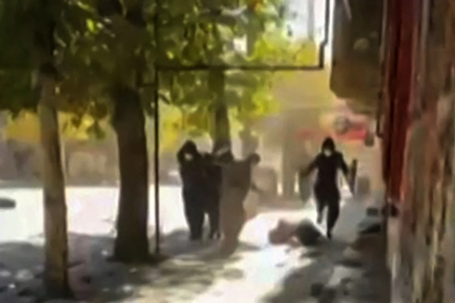 This image grab from UGC video footage posted on November 21, 2022 reportedly shows what appears to be a person on the ground as Iranian protesters take cover while security forces fire live ammunition in a street in the Kurdish-majority city of Javanrud, in the western province of Kermanshah. (Photo by UGC / AFP)
