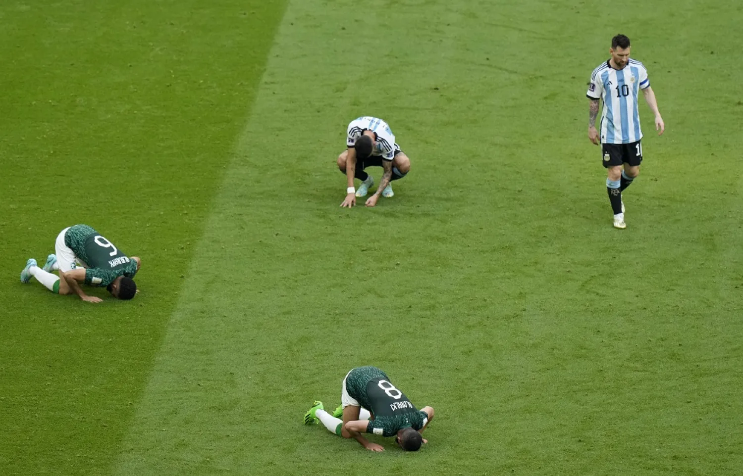 Argentina's Lionel Messi, right, leaves the field as Saudi Arabia's Mohammed Al-Burayk, left, and teammate Abdulelha Al-Malki, below, celebrate after their win in the World Cup group C soccer match between Argentina and Saudi Arabia at the Lusail Stadium in Lusail, Qatar, Tuesday, Nov. 22, 2022. (AP)