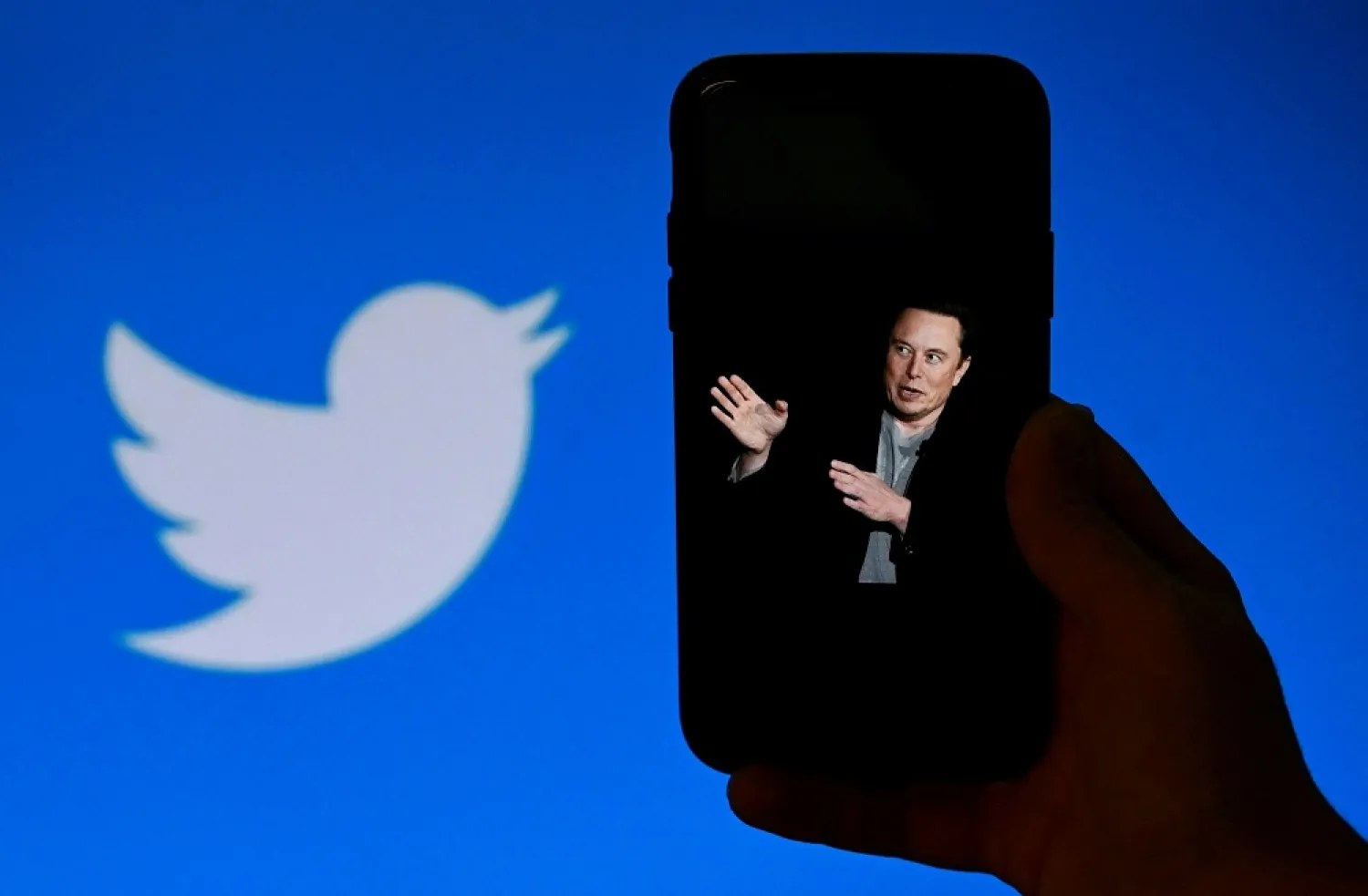 In this file photo taken on October 4, 2022, a phone screen displays a photo of Elon Musk with the Twitter logo shown in the background, in Washington, DC. (AFP)