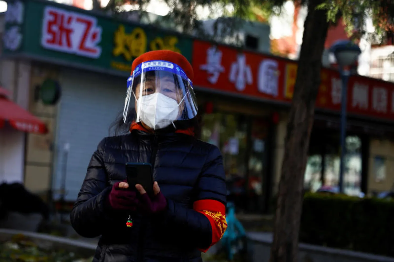 امرأة ترتدي القناع الواقي من فيروس كورونا خلال تجولها في احد شوارع بكين (رويترز)