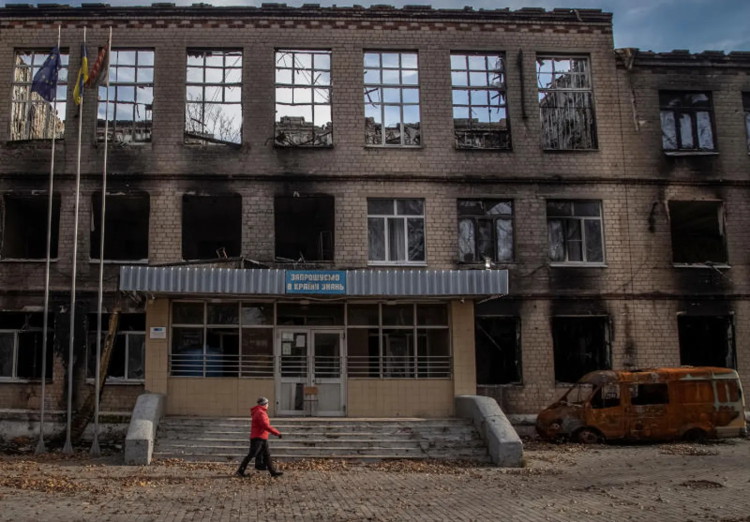رجل يمر من أمام مدرسة دمرها القصف الروسي في أفدييفكا بمنطقة دونيتسك (رويترز)