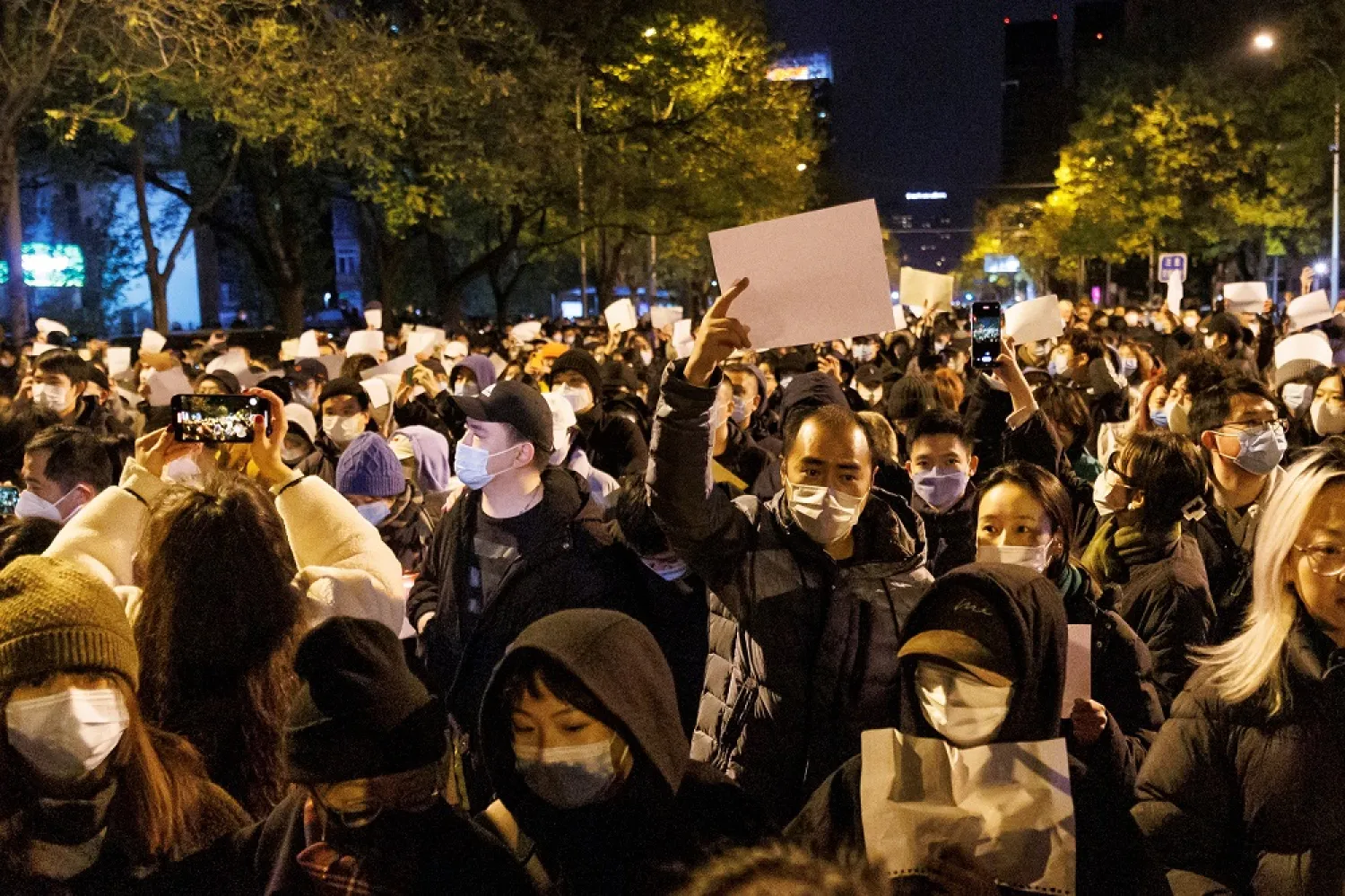 People hold white sheets of paper in protest of coronavirus disease (COVID-19) restrictions, after a vigil for the victims of a fire in Urumqi, as outbreaks of the coronavirus disease continue in Beijing, China, November 27, 2022. (Reuters)