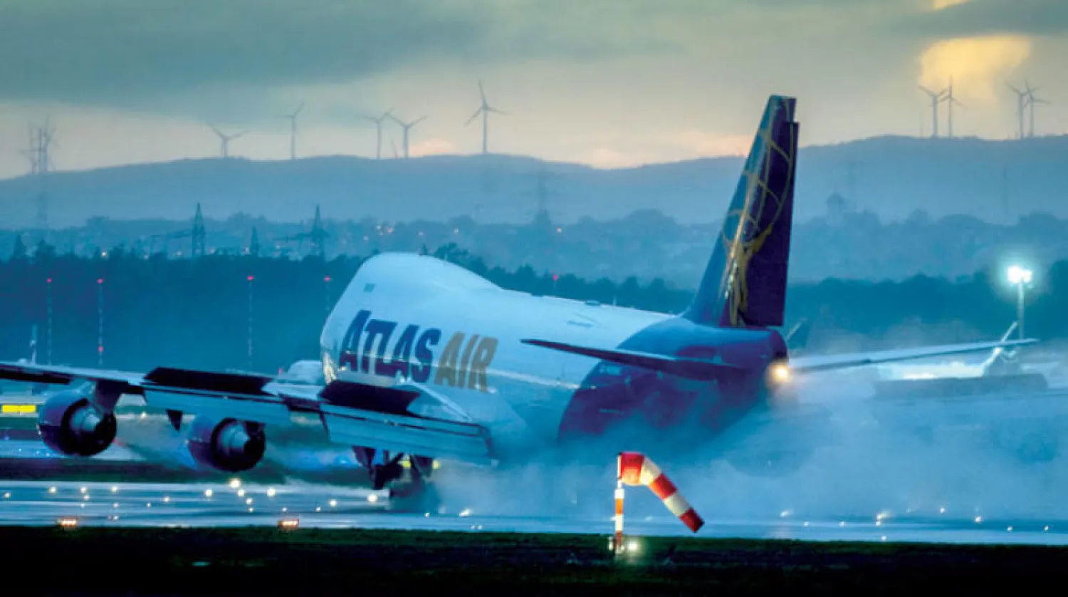 طائرة تهبط في المطار الدولي مع توربينات رياح في الخلفية في فرانكفورت، ألمانيا (أ.ب)