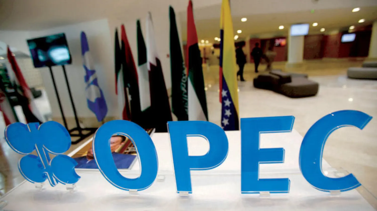 شعار {أوبك} على باب المنظمة بمقرها الرئيسي في فيينا وخلفه أعلام الدول الأعضاء (رويترز)