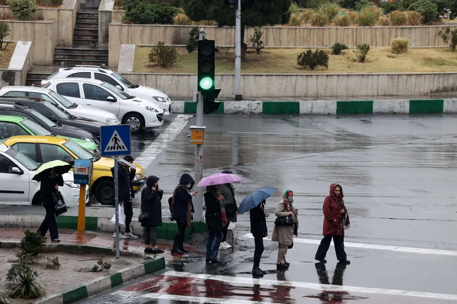 Iranians walks in the street on a rainy day in the capital Tehran, on December 4, 2022. (AFP)