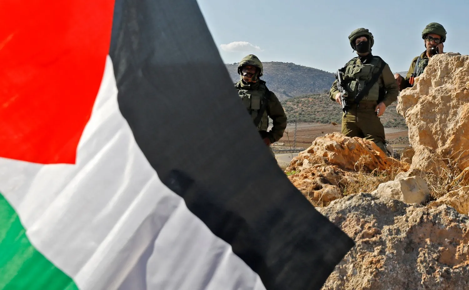 Israeli security forces take position as Palestinians wave national flags during a protest in Beit Dajan, east of the occupied West Bank city of Nablus, against the establishment of Israeli outposts, on December 2, 2022. (AFP)
