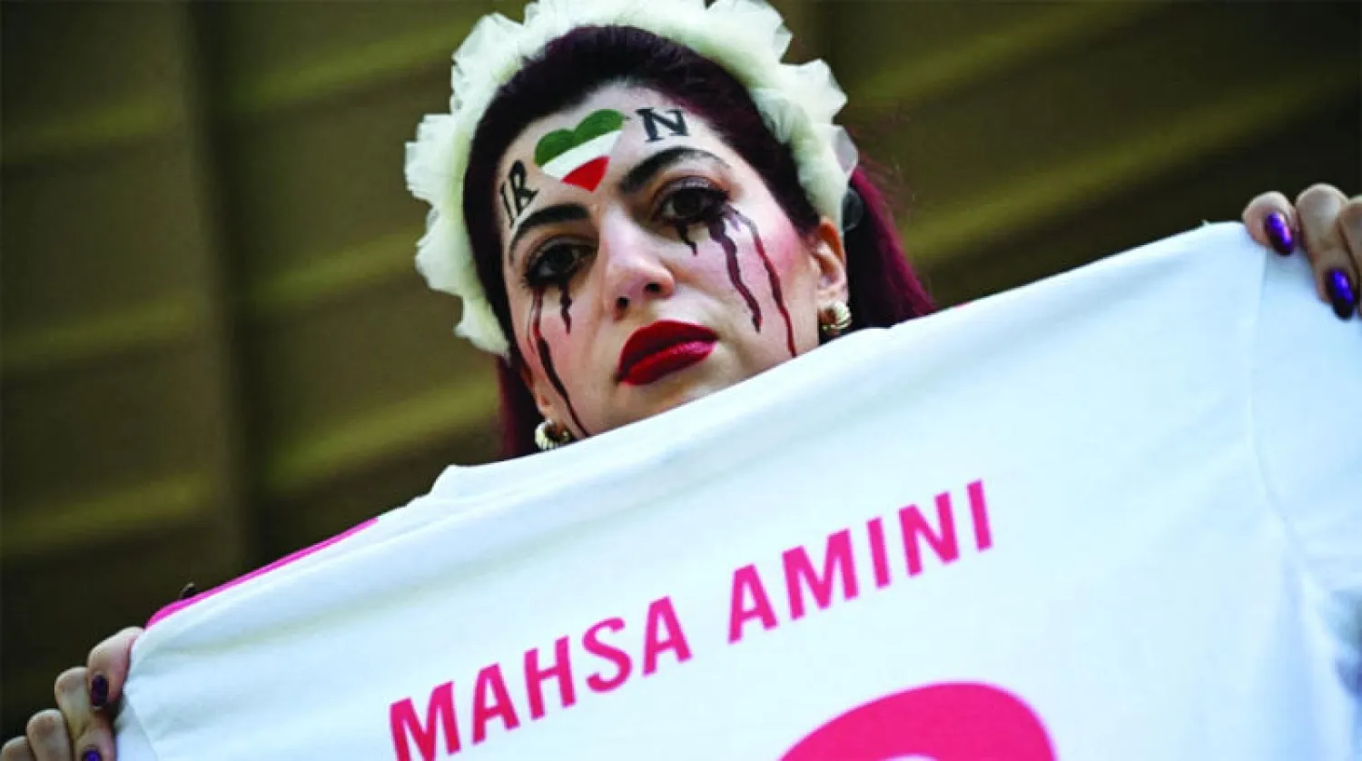 إيرانية ترفع لافتة كتب عليها اسم مهسا أميني أثناء إحدى مباريات كأس العالم (رويترز)