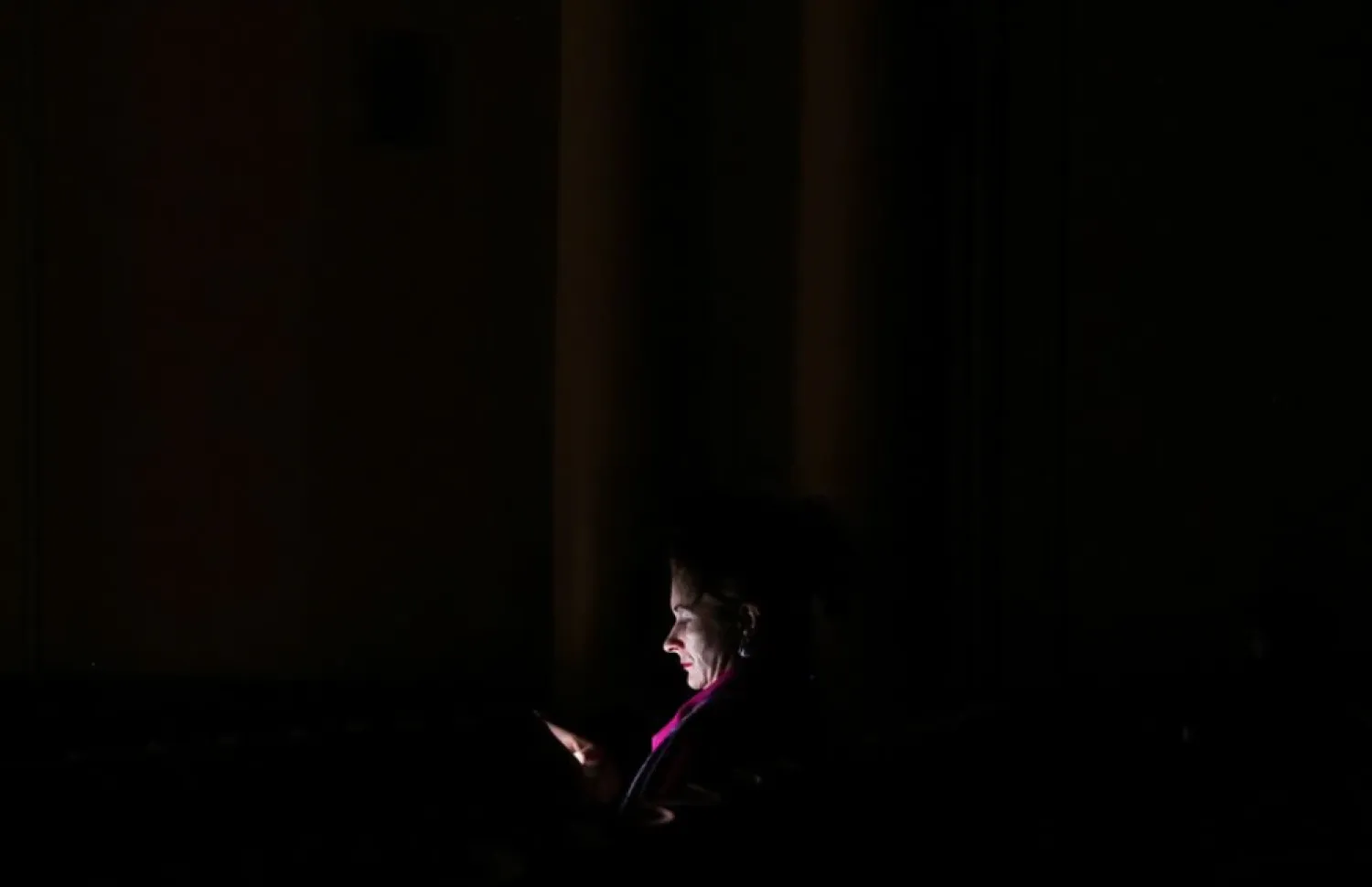  A woman uses a mobile phone to illuminate herself while attending the Kyiv Chamber Orchestra performance during power outages at the The National Philharmonic of Ukraine in Kyiv, Ukraine, December 3, 2022. REUTERS/Shannon Stapleton








