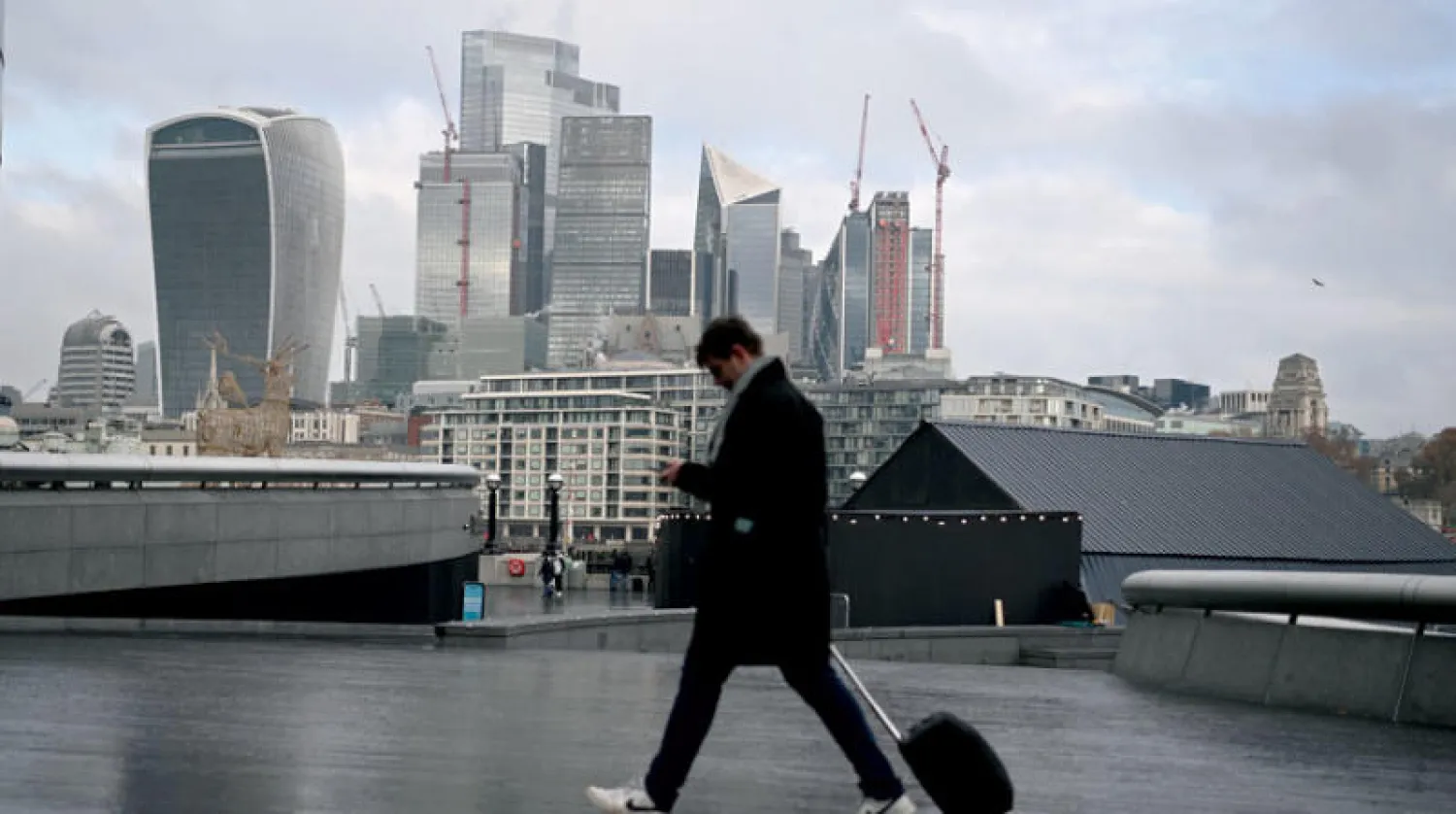 أحد المارة يعبر أمام الحي المالي وسط العاصمة البريطانية لندن (إ.ب.أ)