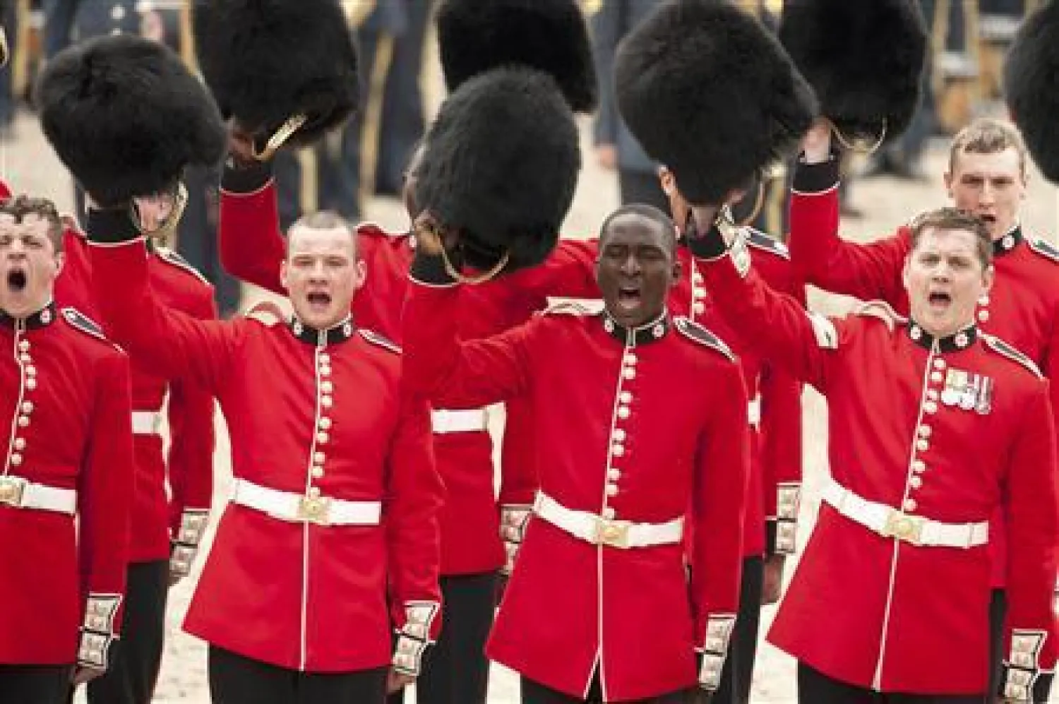 عناصر من الحرس الملكي البريطاني يرفعون قبعاتهم (رويترز)