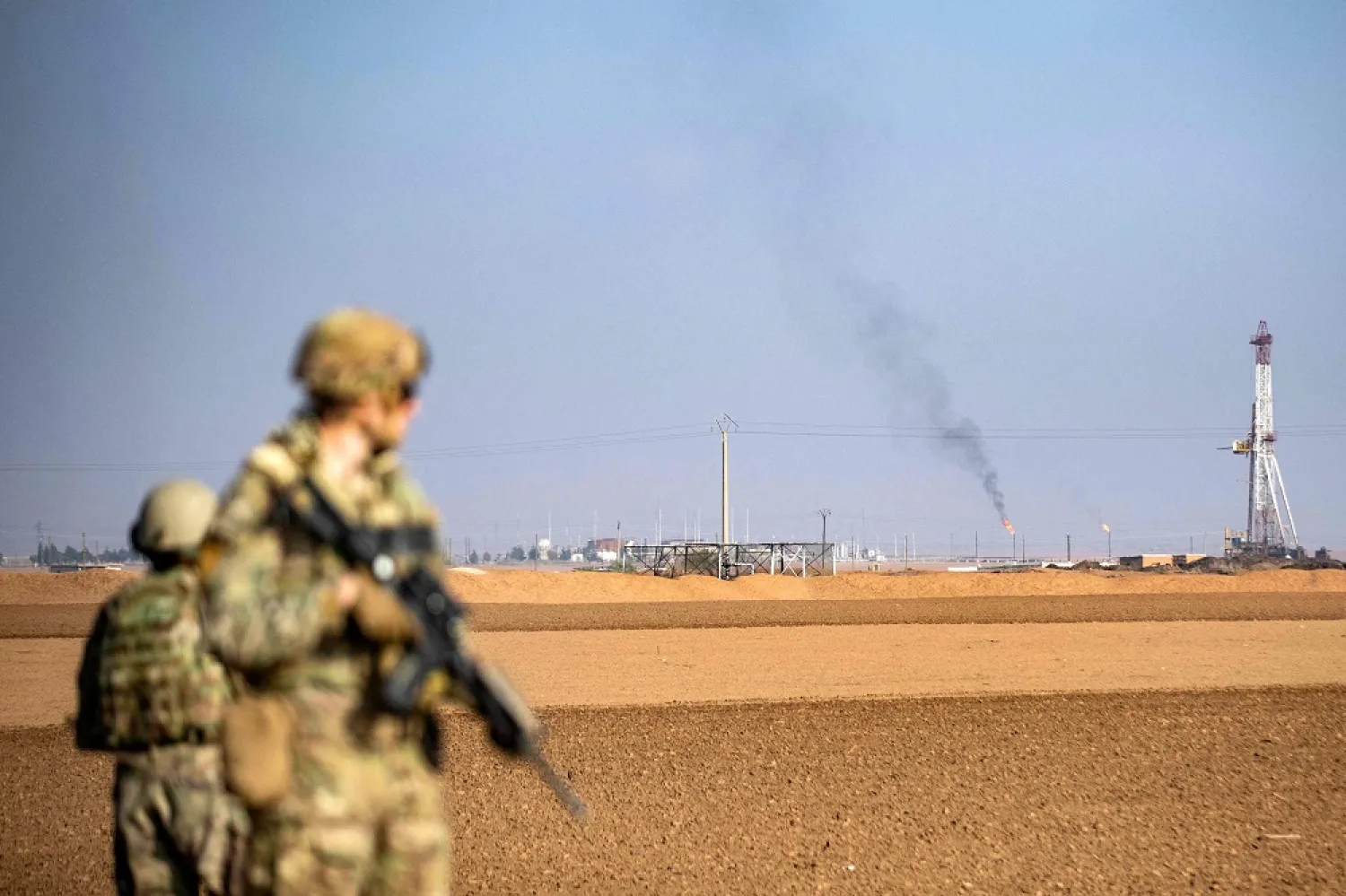 US soldiers look towards a flare stack at a local oil field as they patrol the countryside of Rumaylan (Rmeilan) in Syria's northeastern Hasakeh province near the border with Türkiye, on December 4, 2022. (AFP)