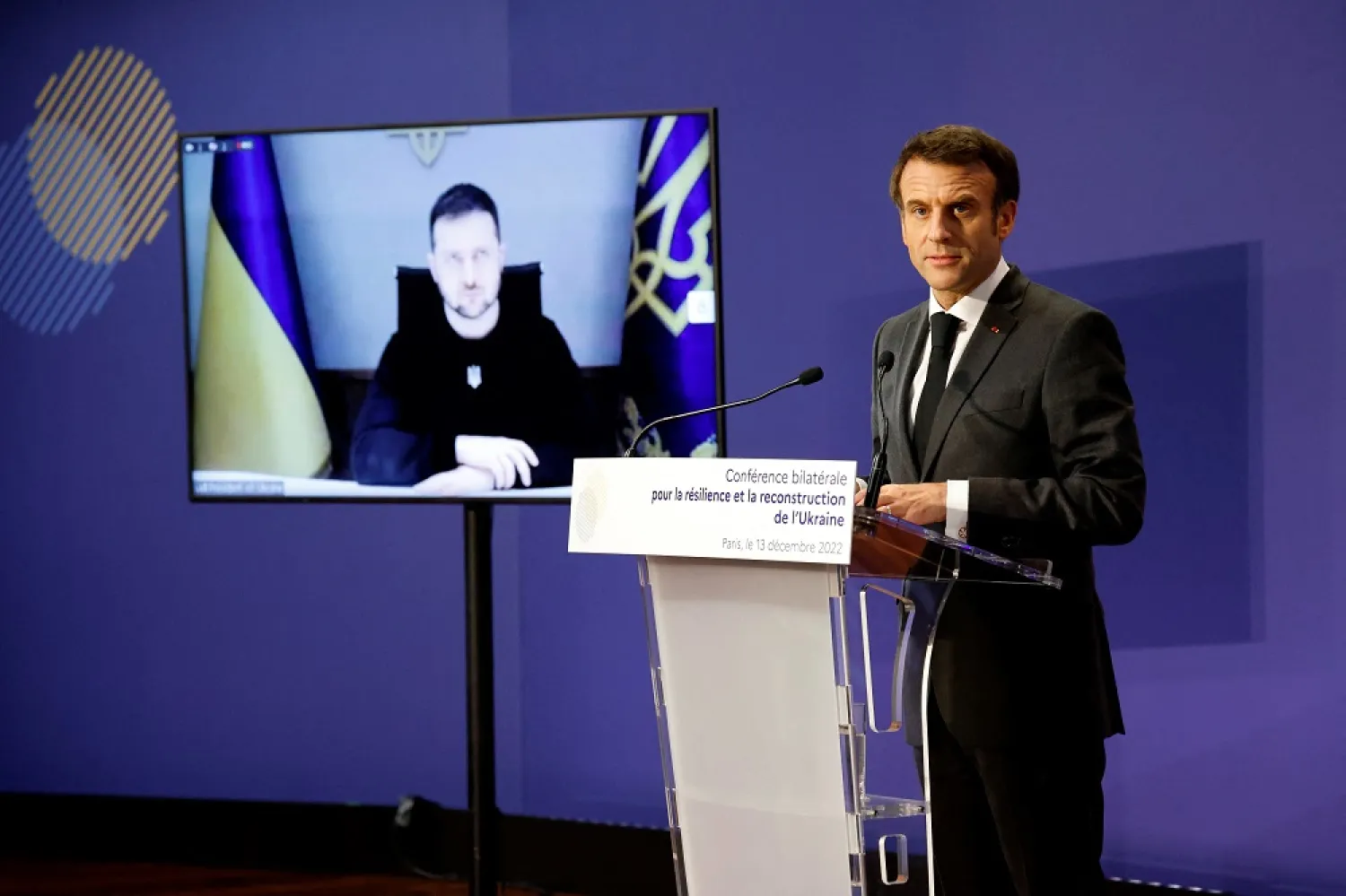 Ukrainian President Volodymyr Zelensky listens via video link as French President Emmanuel Macron delivers a speech during the French-Ukrainian conference for resilience and reconstruction at the Ministry of Economy in Paris, France December 13, 2022. (Reuters)