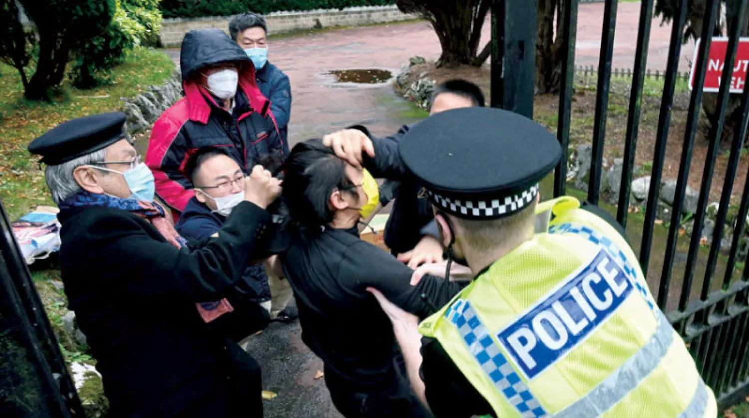 شرطي بريطاني يحاول التدخل خلال مواجهات بين متظاهرين وعاملين في القنصلية الصينية بمانشستر (أ.ف.ب)