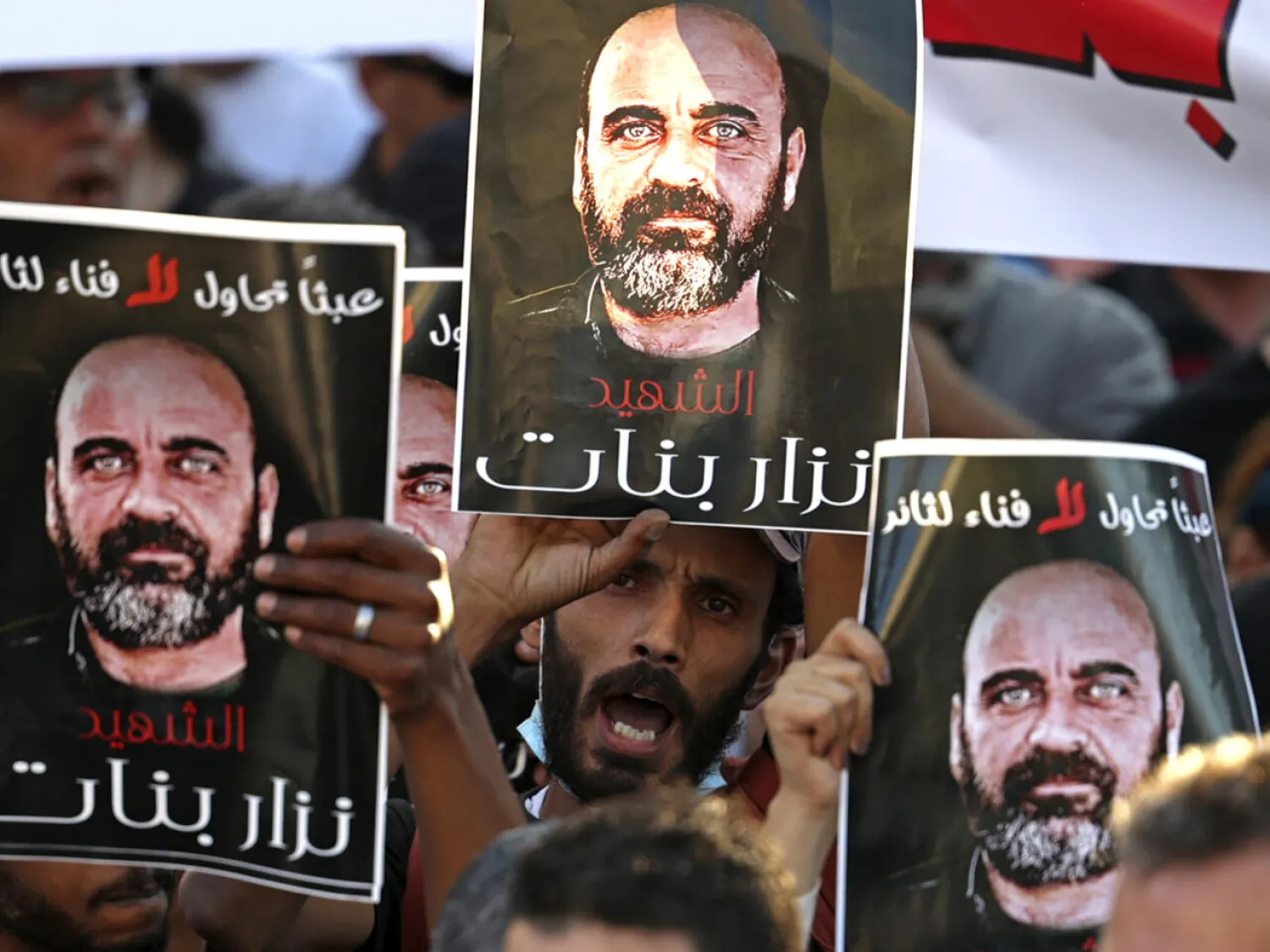 Palestinians, in this August 2021 photograph, hold posters of Nizar Banat, who died in Palestinian custody. ABBAS MOMANI / AFP

