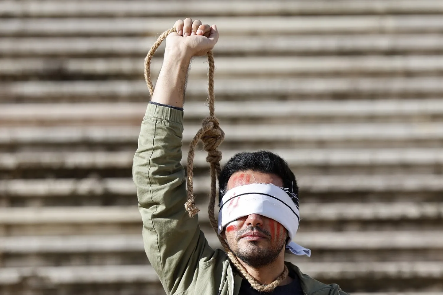 A demonstrator from the Iranian Portuguese community protests in front of the Parliament building following Iran's sentencing to death and public execution of two young demonstrators, Mohsen Shekari and Majidreza Rahnavard, for participating in demonstrations against the regime, in Lisbon, Portugal, 16 December 2022. (EPA)