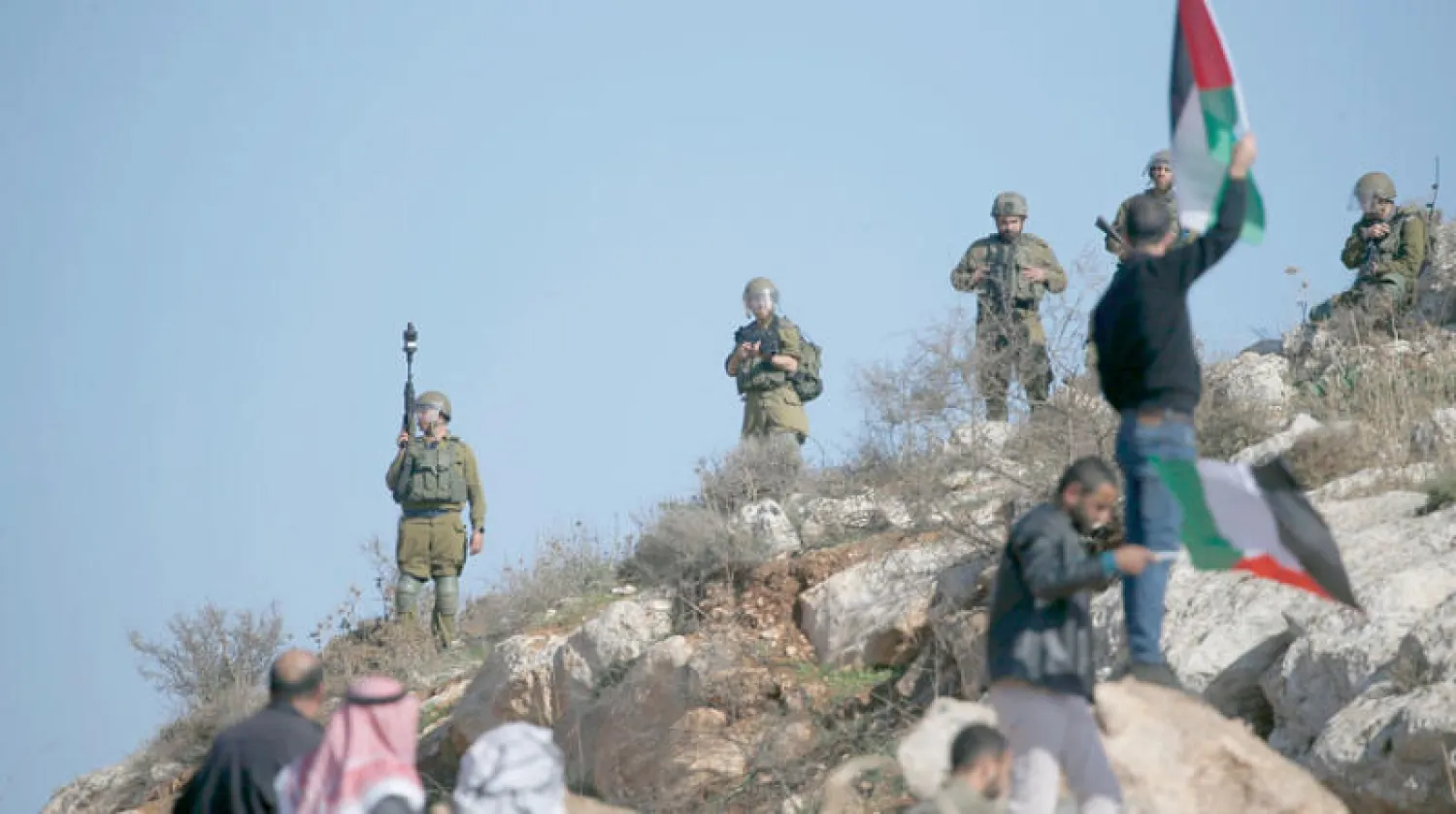 فلسطينيون بمواجهة جنود إسرائيليين احتجاجاً على مستوطنات إسرائيلية على أراضٍ بالضفة 16 ديسمبر (إ.ب.أ)