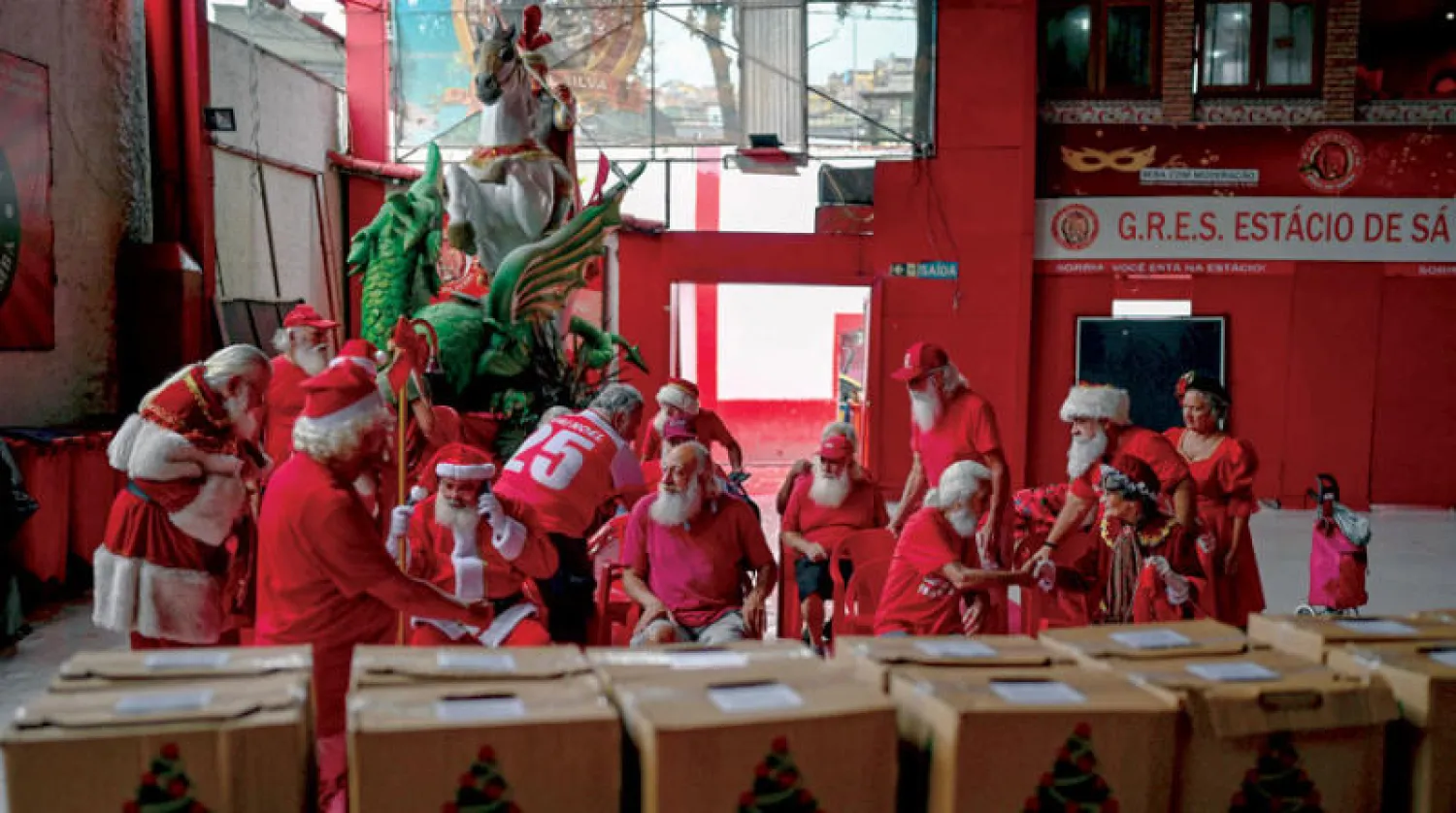 مجموعة من مجسدي «سانتا كلوز» ينتظرون تسلم سلال طعام العيد (أ.ف.ب)