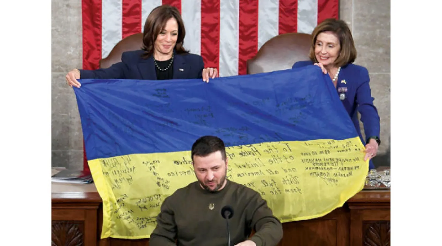 كمالا هاريس ونانسي بيلوسي تحملان علماً أوكرانياً موقعاً أهداه لهما زيلينسكي الأربعاء (د.ب.أ)