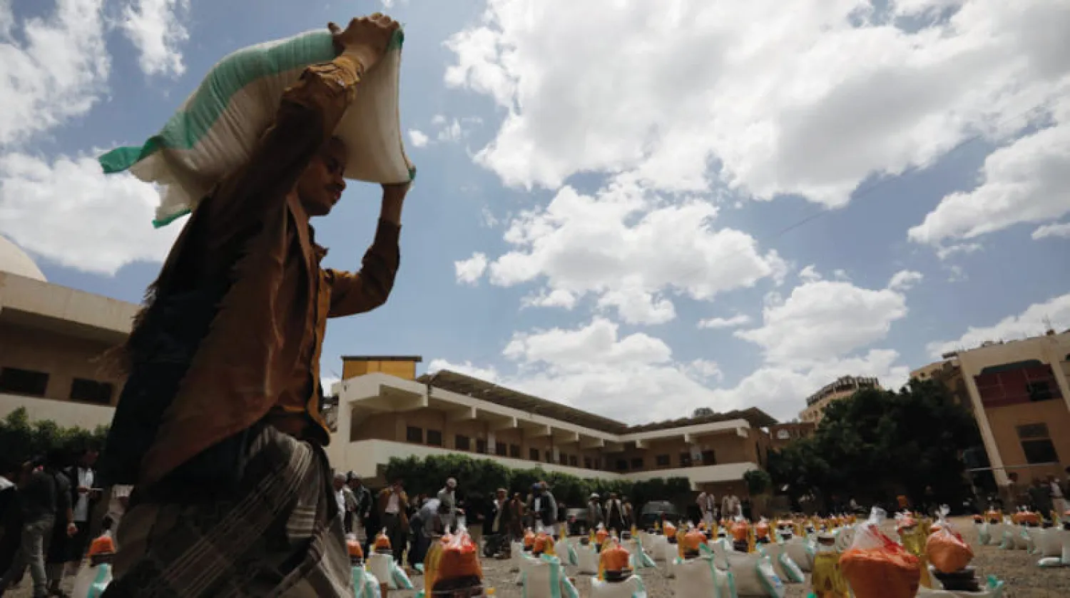 عامل إغاثة يحمل حصة غذائية مقدمة من جمعية خيرية في صنعاء (إ.ب.أ)