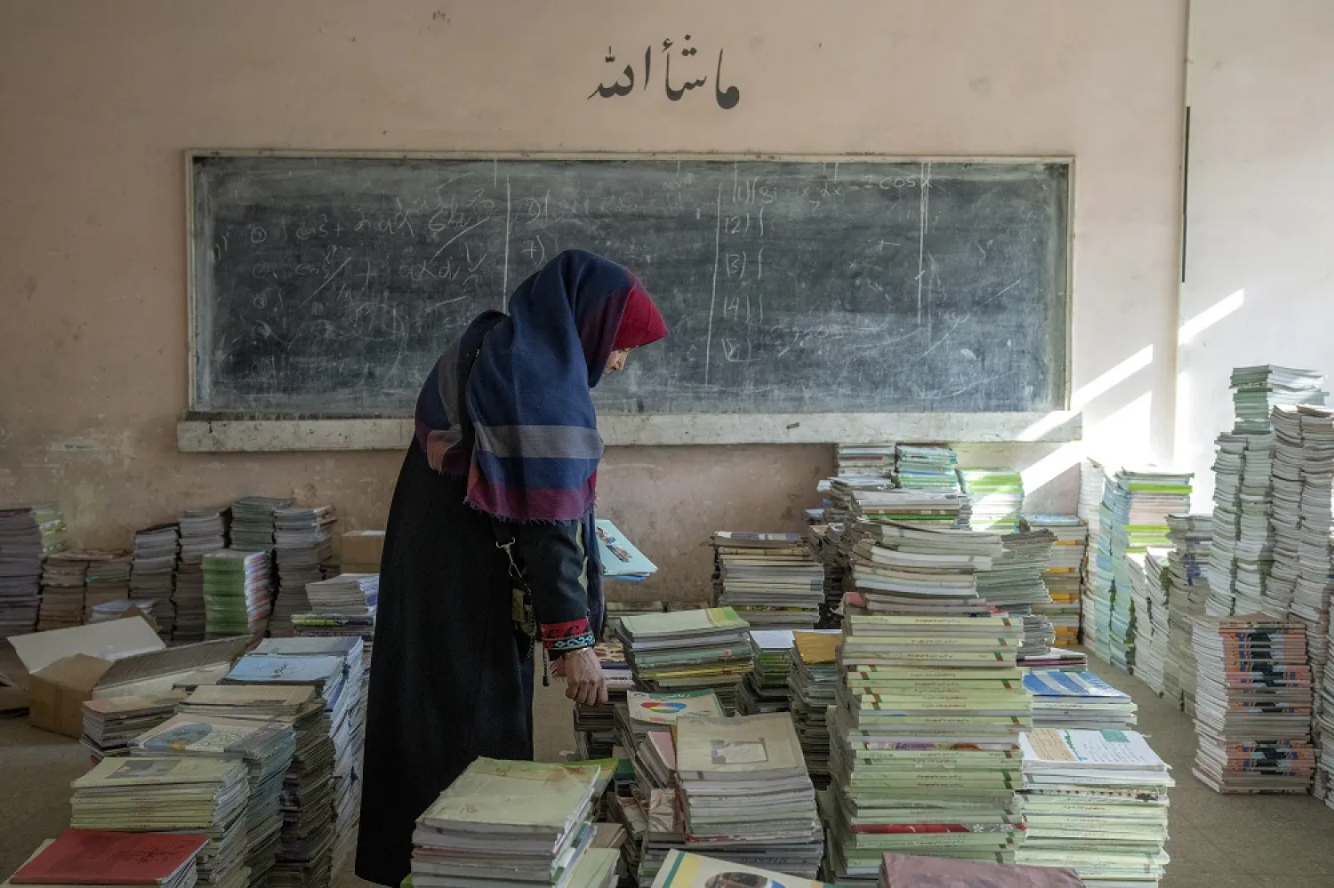 Amanah Nashenas, 45-year-old an Afghan teacher, collects books in a school in Kabul, Afghanistan, Thursday, Dec. 22, 2022. (AP)