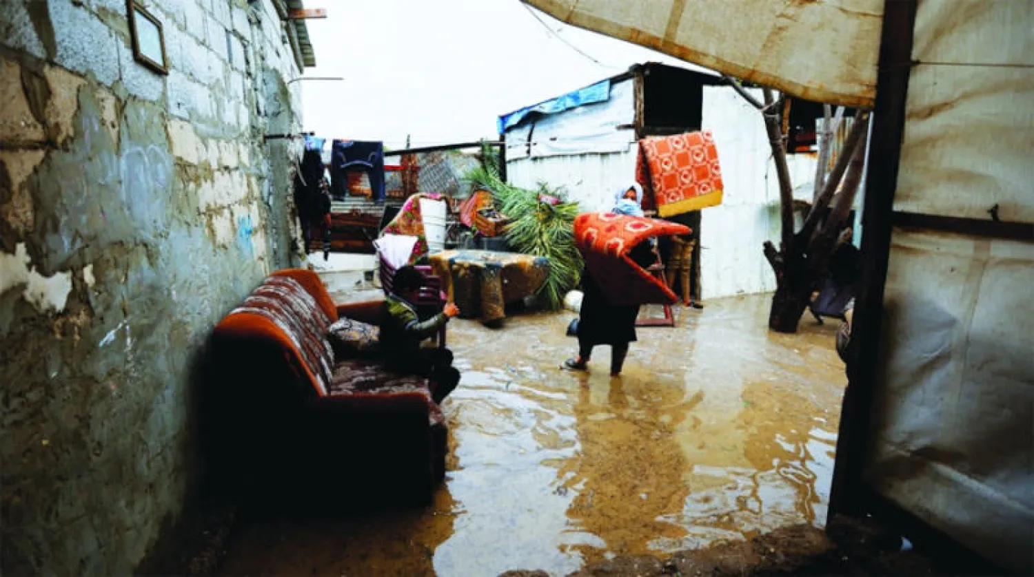 فلسطينية تزيل متعلقات عائلتها بعد أن غمرت مياه الأمطار منزلها في خان يونس جنوب غزة (رويترز)