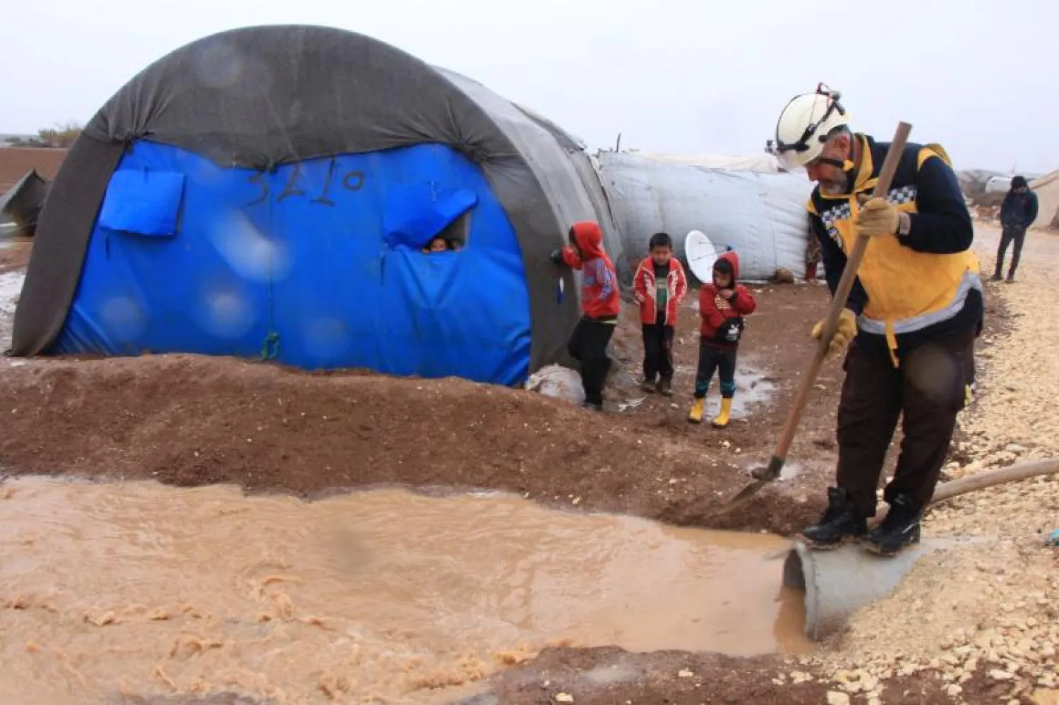 عامل من منظمة إنسانية يتعامل مع السيول الناتجة عن الأمطار