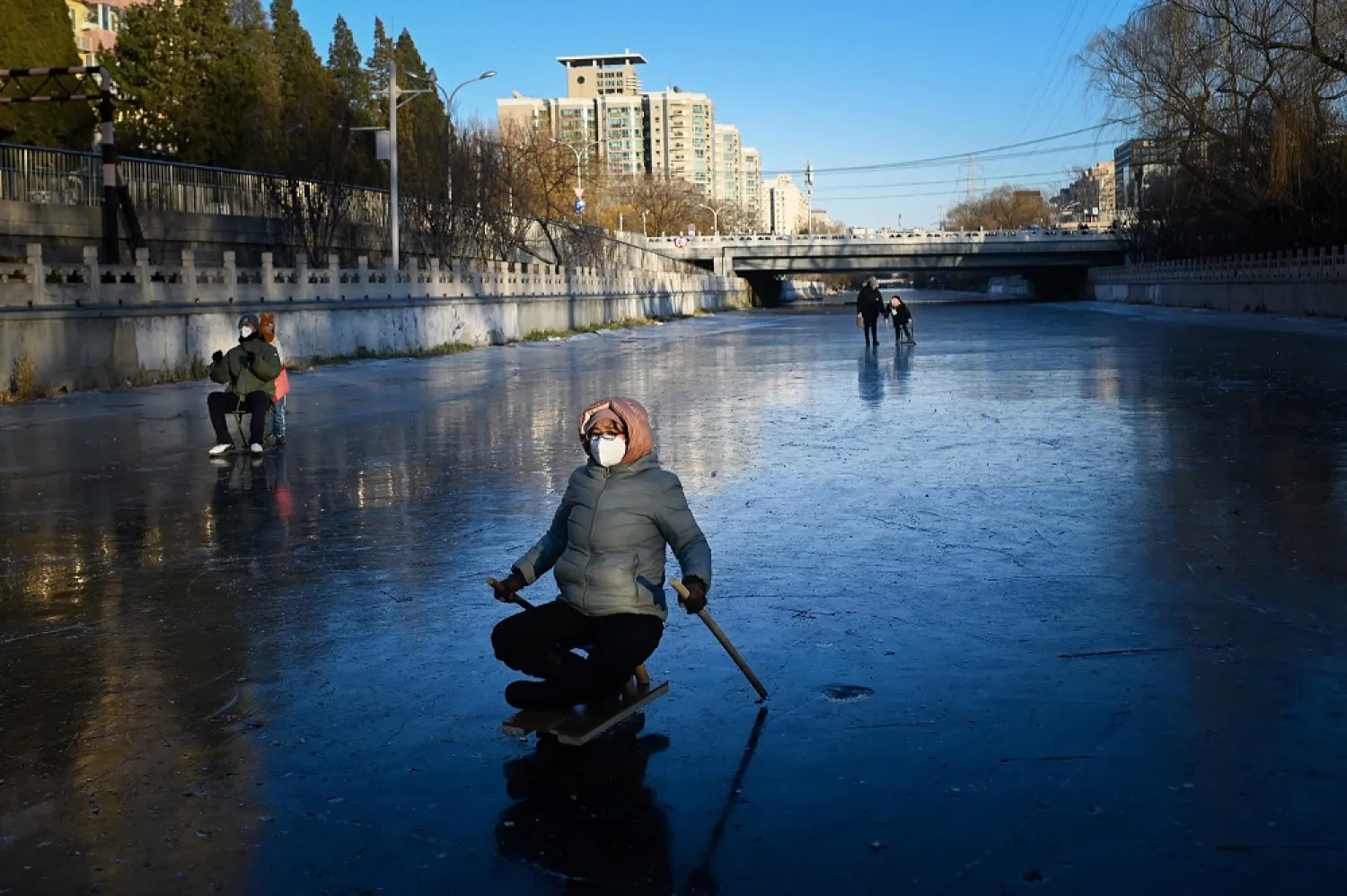 A woman rides on a sled on a frozen river in Beijing on December 27, 2022. (AFP)