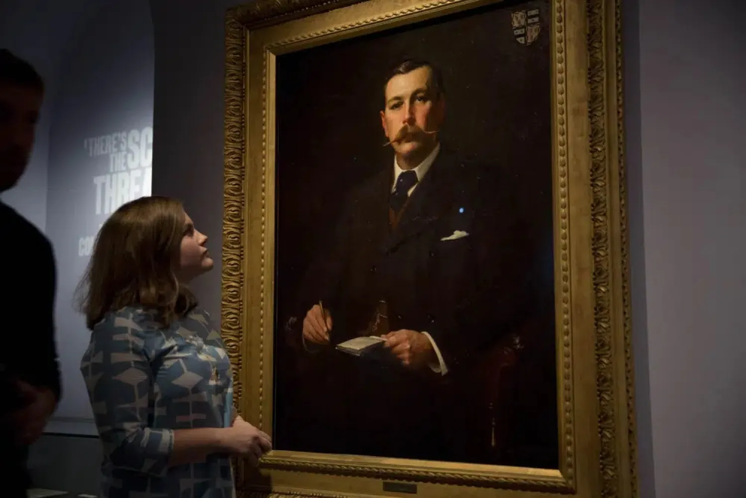A Museum of London employee poses for photographers next to an 1897 oil on canvas portrait of Sherlock Holmes author Sir Arthur Conan Doyle by illustrator Sidney Paget on display as part of the exhibition "Sherlock Holmes: The Man Who Never Lived and Will Never Die" at the Museum of London in London, Oct. 16, 2014. (AP) 