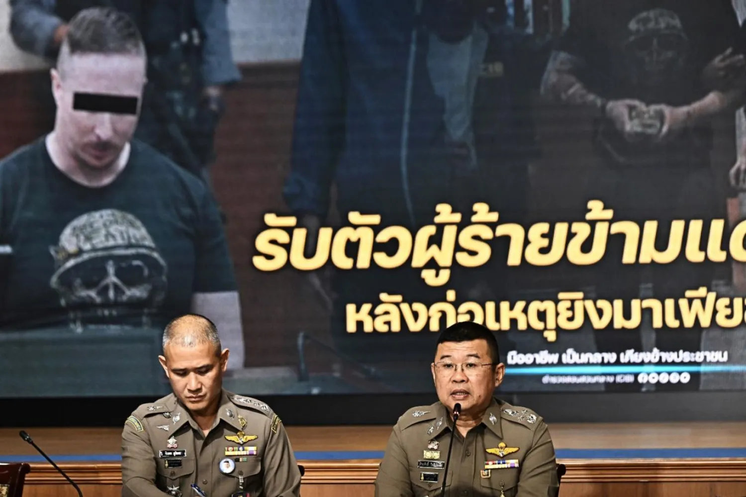 Ulusal polis şefi Damrongsak Kittiprapas (sağda), 4 Şubat 2022'de Phuket'te gangster Jimi "Slice" Sandhu'yu öldürdüğü şüphesiyle aranan Kanadalı Matthew Dupre'nin (ekranda) iadesine ilişkin 29 Mayıs 2023'te Tayland'ın Bangkok kentinde Suçla Mücadele Birimi'nde düzenlenen basın toplantısında konuşurken (AFP)