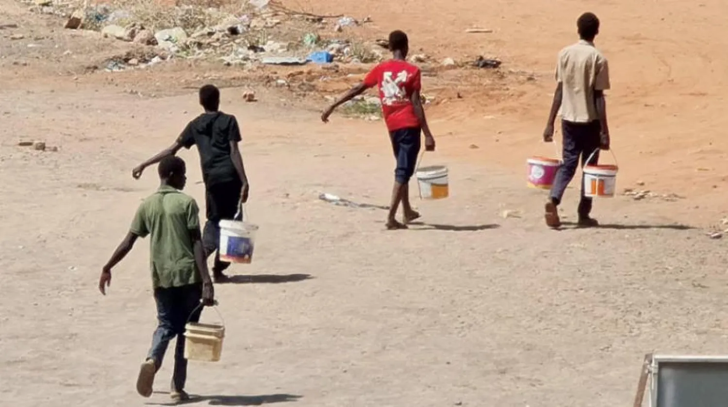 Boys carrying buckets filled with water in a street in Khartoum (AFP)