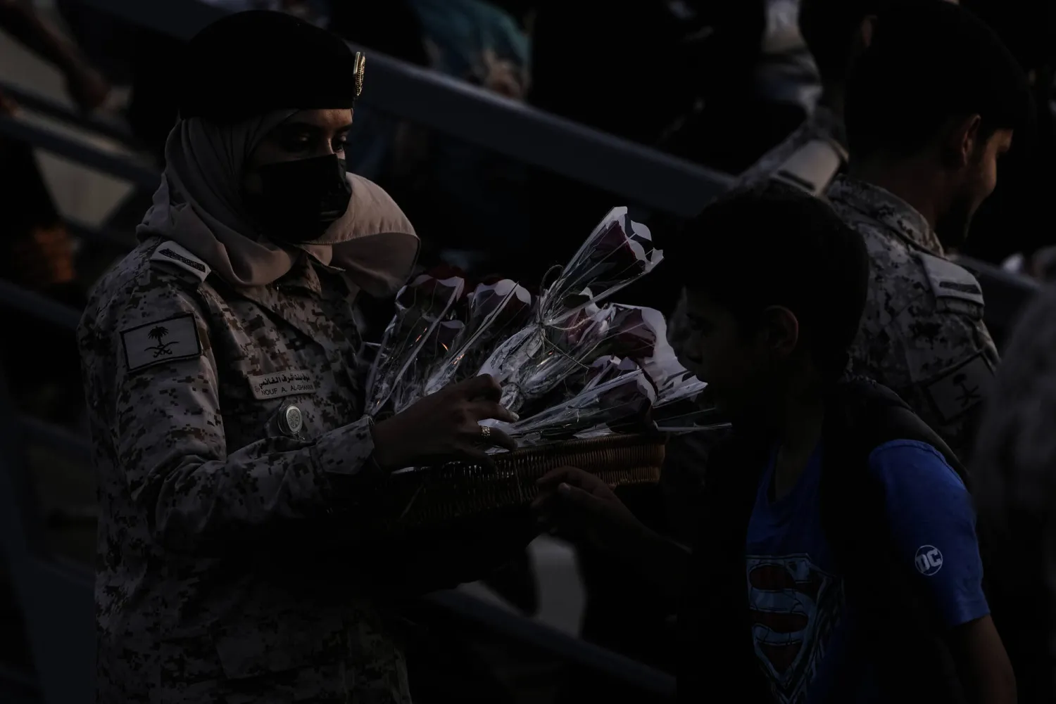 جندية سعودية في ميناء جدة توزع الزهور على اليمنيين الذين أجلوا من بورتسودان (أ.ب)