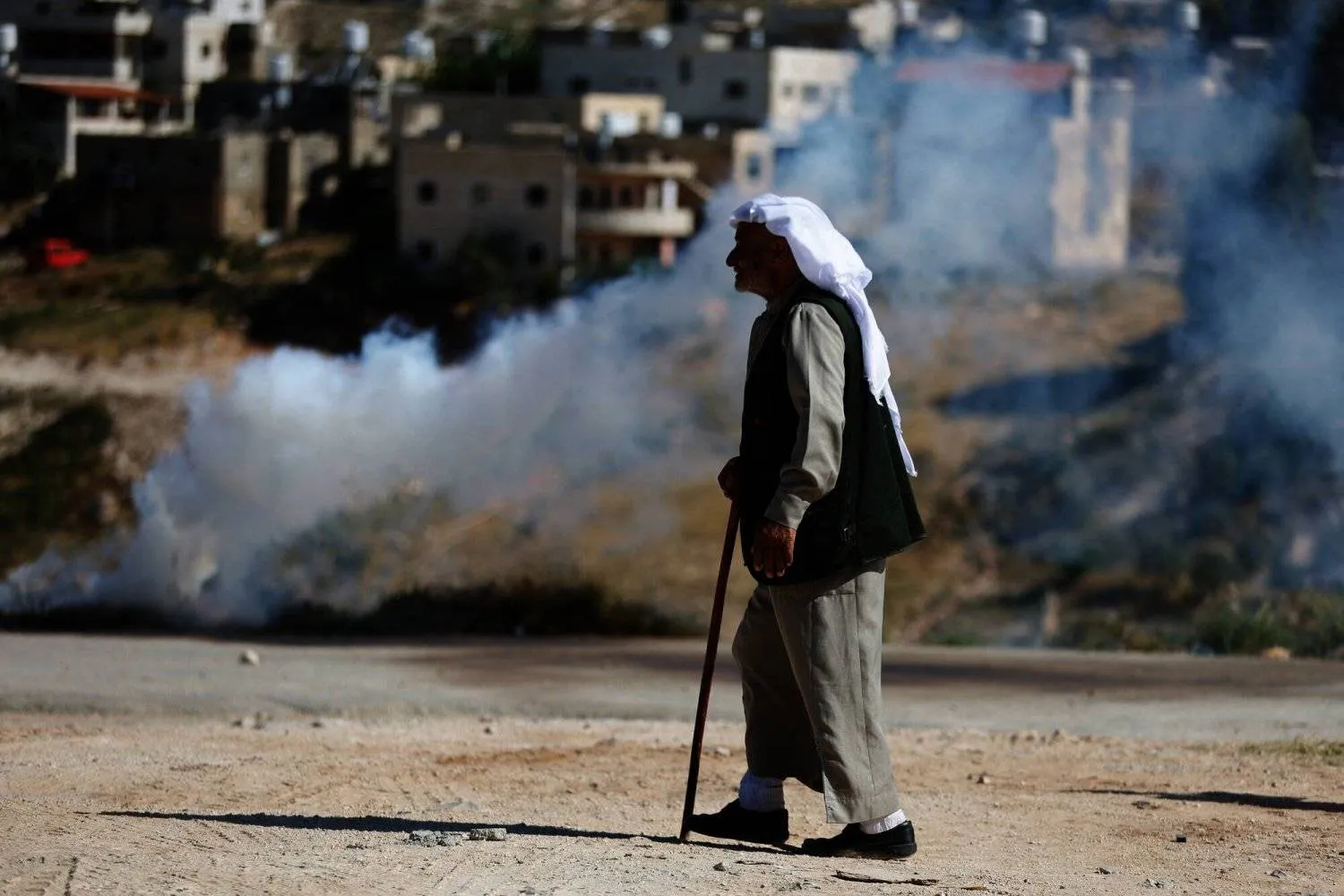 A Palestinian walks near tear gas during clashes between Palestinians and Israeli troops after Israeli machinery demolish a school near Bethlehem in the Israeli-occupied West Bank May 7, 2023. (Reuters) 