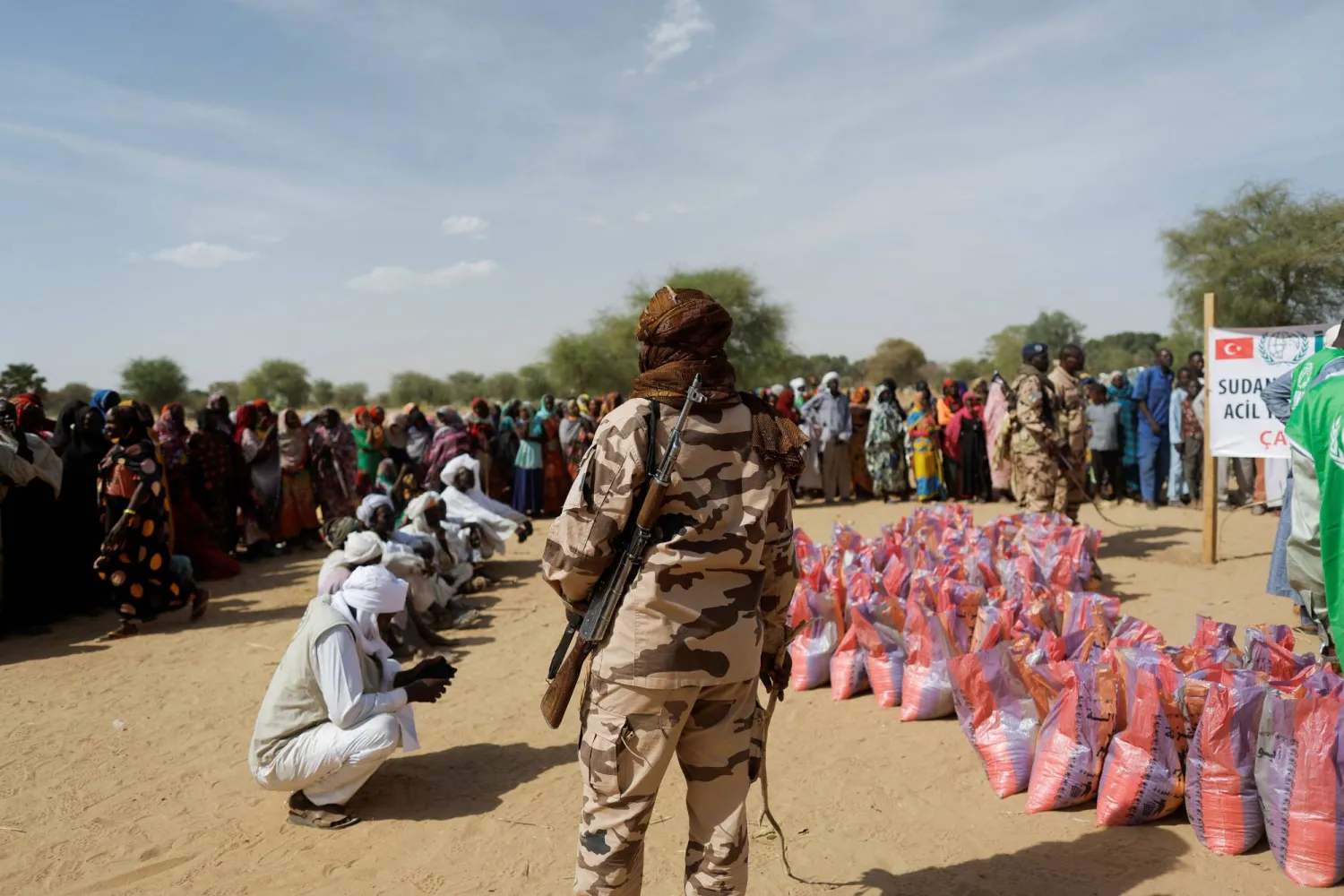 A soldier stands as Sudanese women who fled the violence in their country, wait to receive food supplies from a Turkish aid group (IHH) near the border between Sudan and Chad in Koufroun, Chad May 7, 2023. REUTERS/Zohra Bensemra