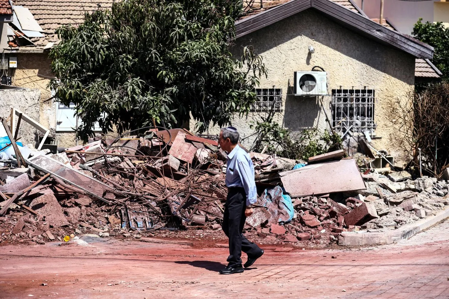 Bir adam, Gazze’den atılan roketin isabet etmesi sonucu hasar gören bir evin önünden geçiyor (Reuters) 