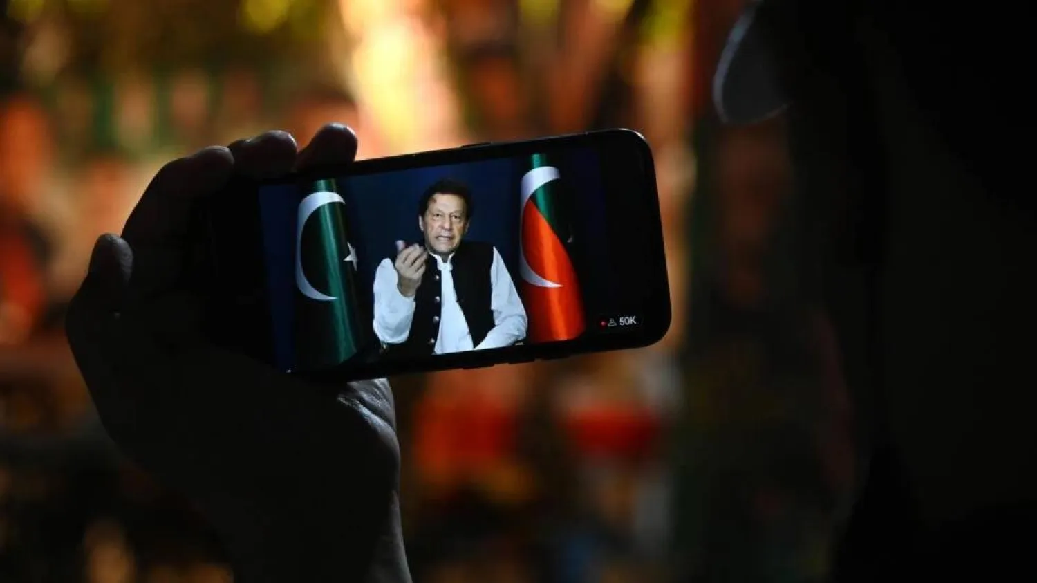 A supporter listens to Pakistani opposition leader Imran Khan's speech on a phone, in Zaman Park in Lahore on May 13, 2023. Arif Ali / AFP