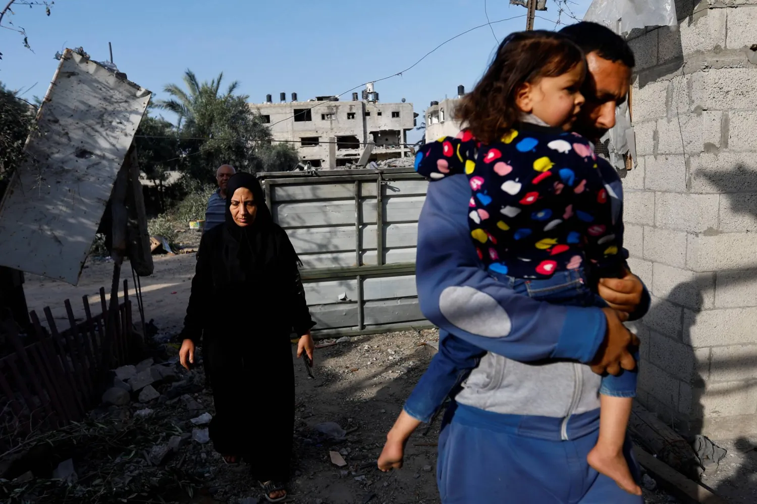 فلسطينيون يعودون إلى منازلهم التي تضررت جراء القصف الإسرائيلي في دير البلح وسط قطاع غزة 14 مايو 2023 (رويترز)