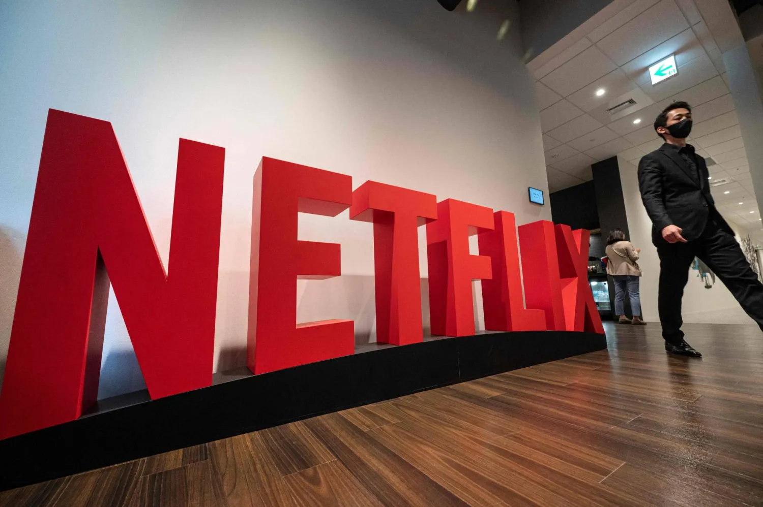 This photo taken on March 24, 2023 shows a man walking past a Netflix display during a media tour and press conference at the office of streaming giant Netflix in the Roppongi area of Tokyo. (Photo by Richard A. Brooks / AFP) 