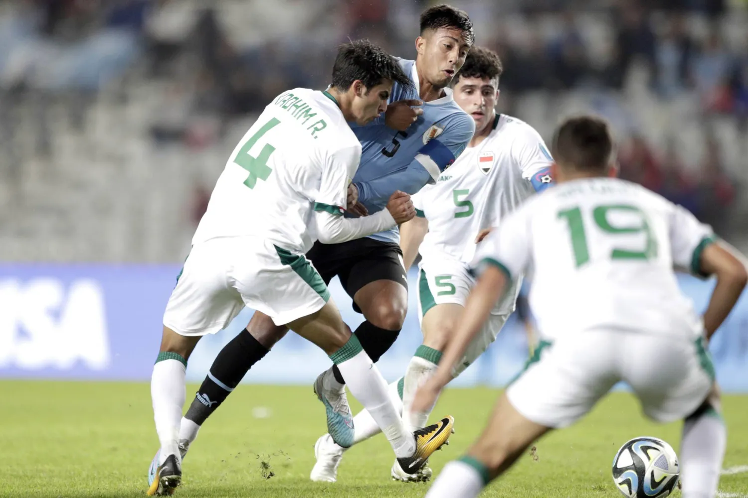 لاعبو العراق في صراع على الكرة أمام لاعب أوروغوياني (إ.ب.أ)