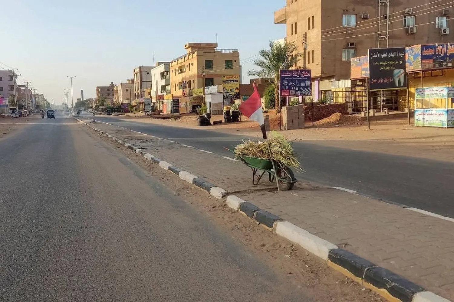 A Sudanese flag rests on a wheelbarrow as a volunteer (not pictured) collects garbage to clean-up a street in southern Khartoum, on May 23, 2023, after a one-week ceasefire between Sudan's army and paramilitary Rapid Support Forces officially went into force. (AFP) 